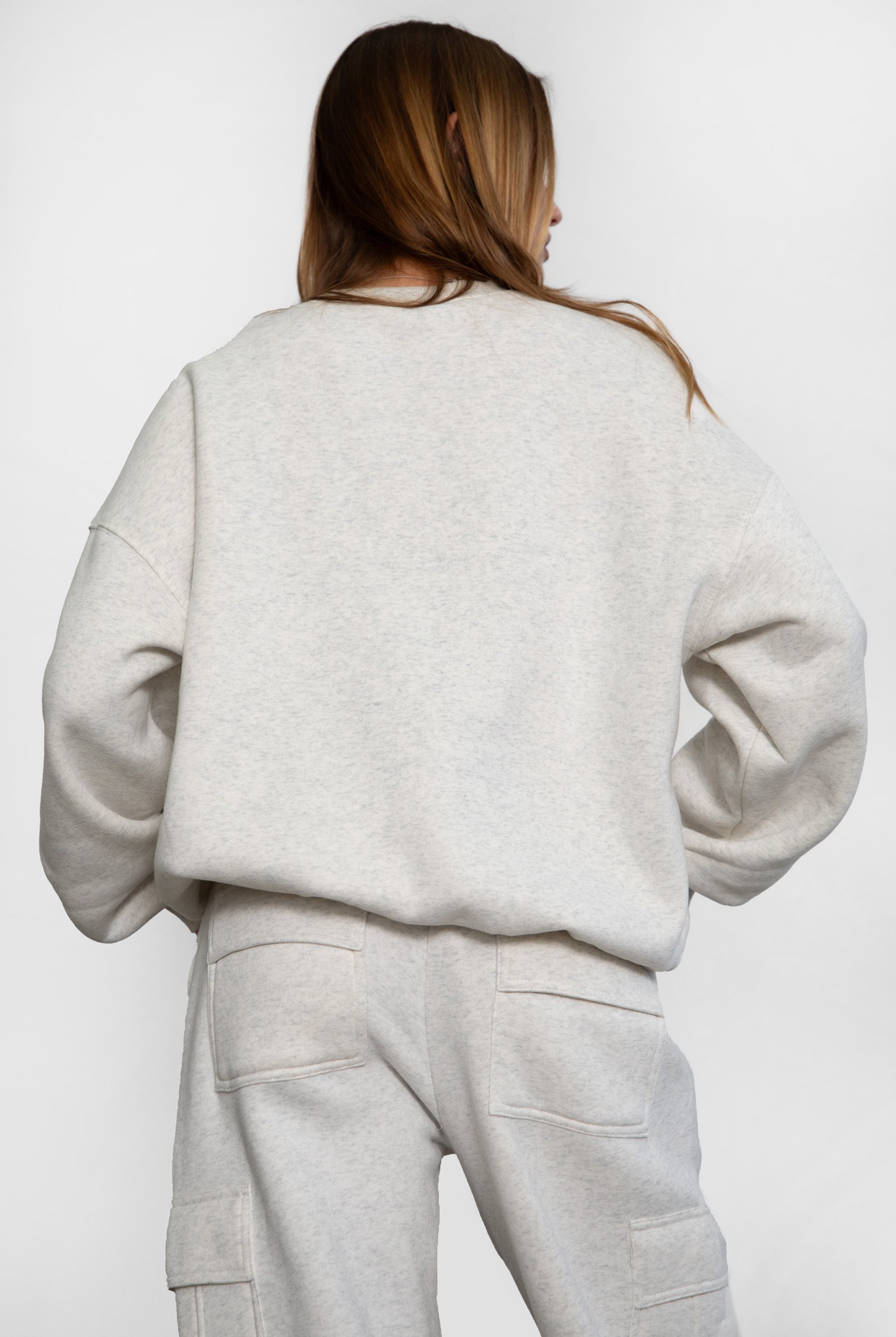 Person wearing a heather white sweater and pants set on a white background