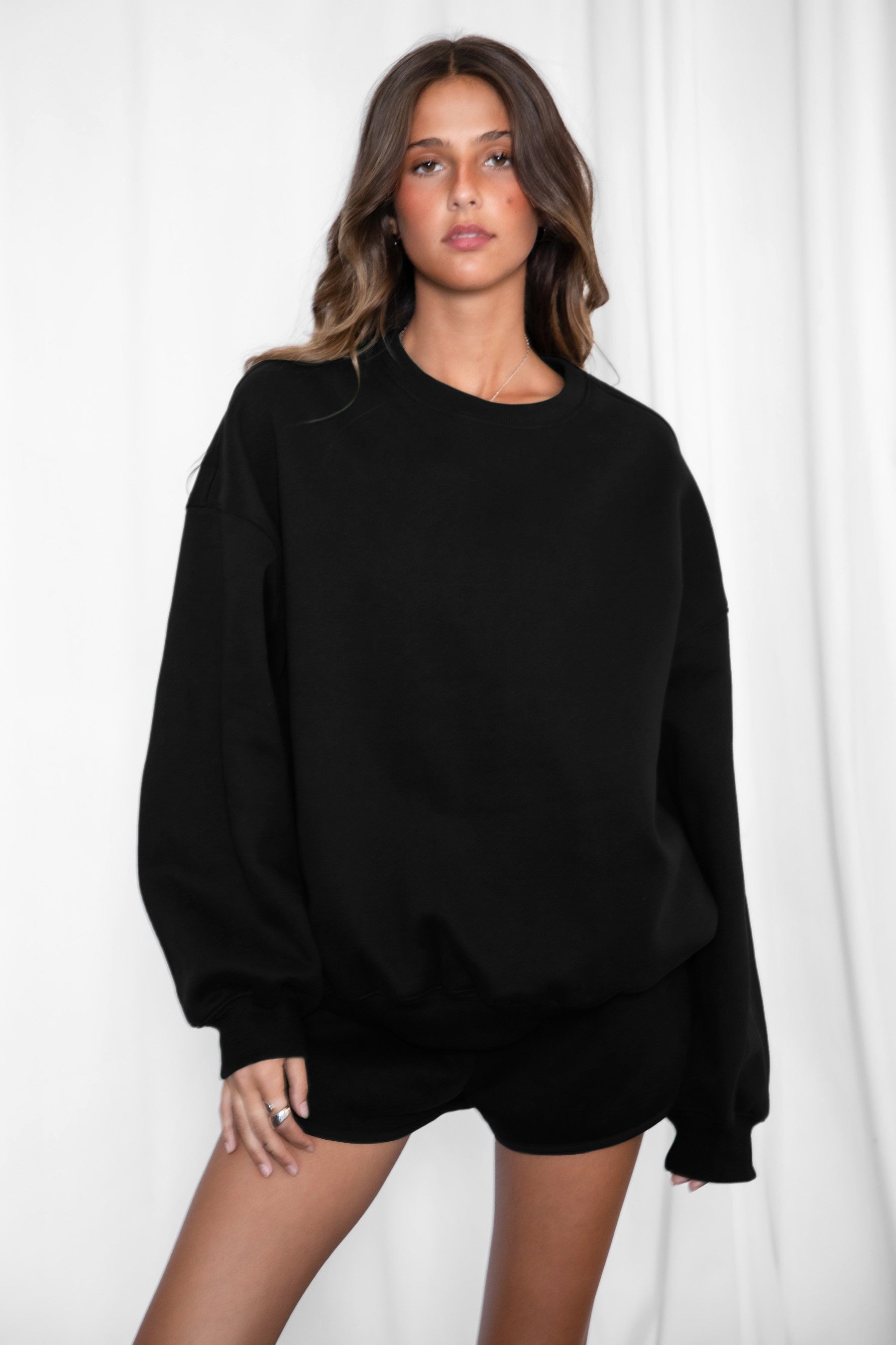 Person wearing a black oversized sweatshirt against a white background