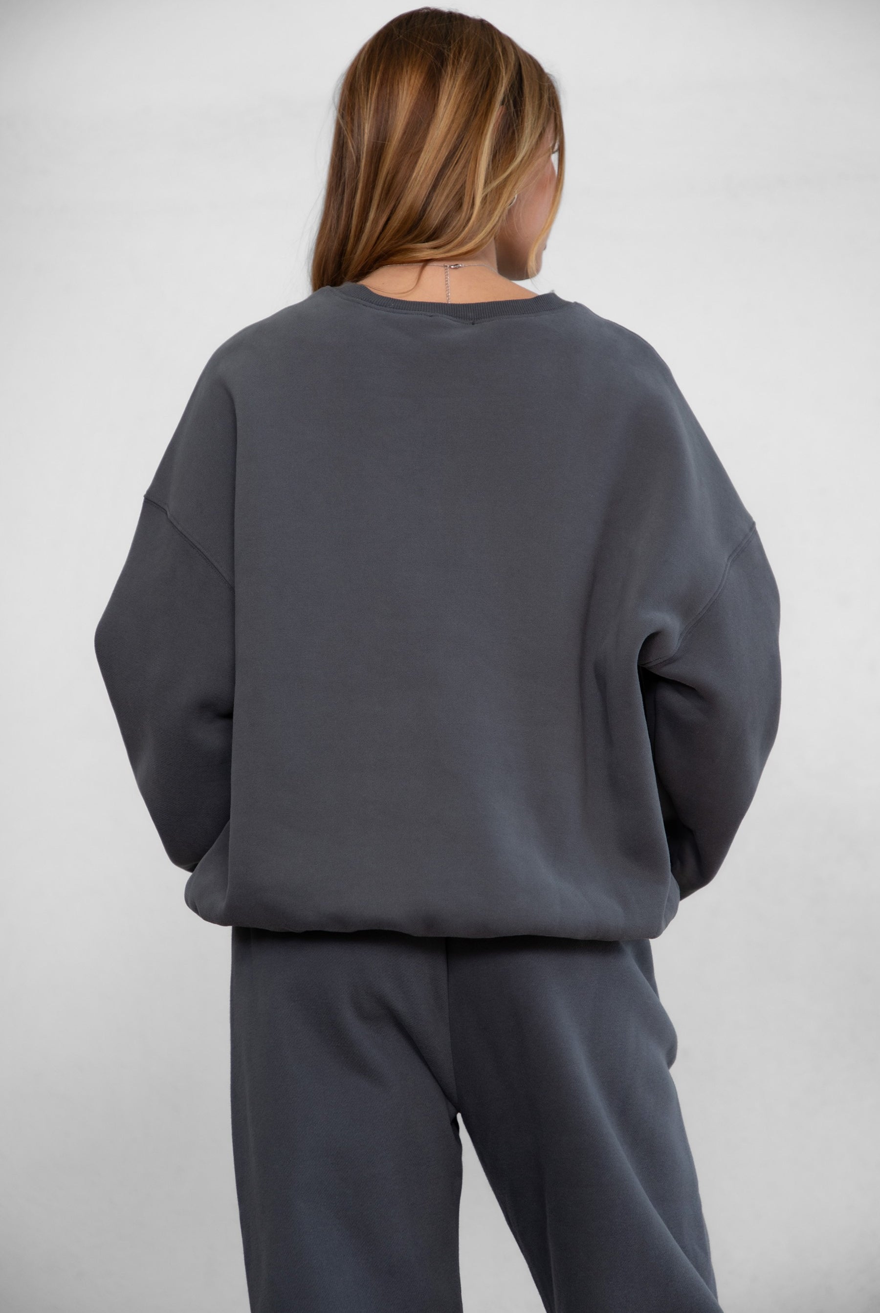Person wearing a gray sweatshirt and pants on a white background