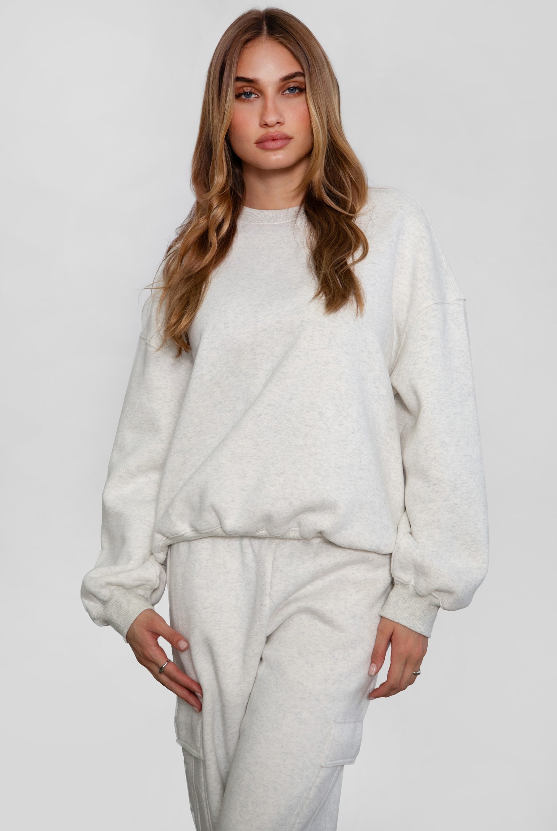 Person wearing a heather white sweater and pants set on a white background