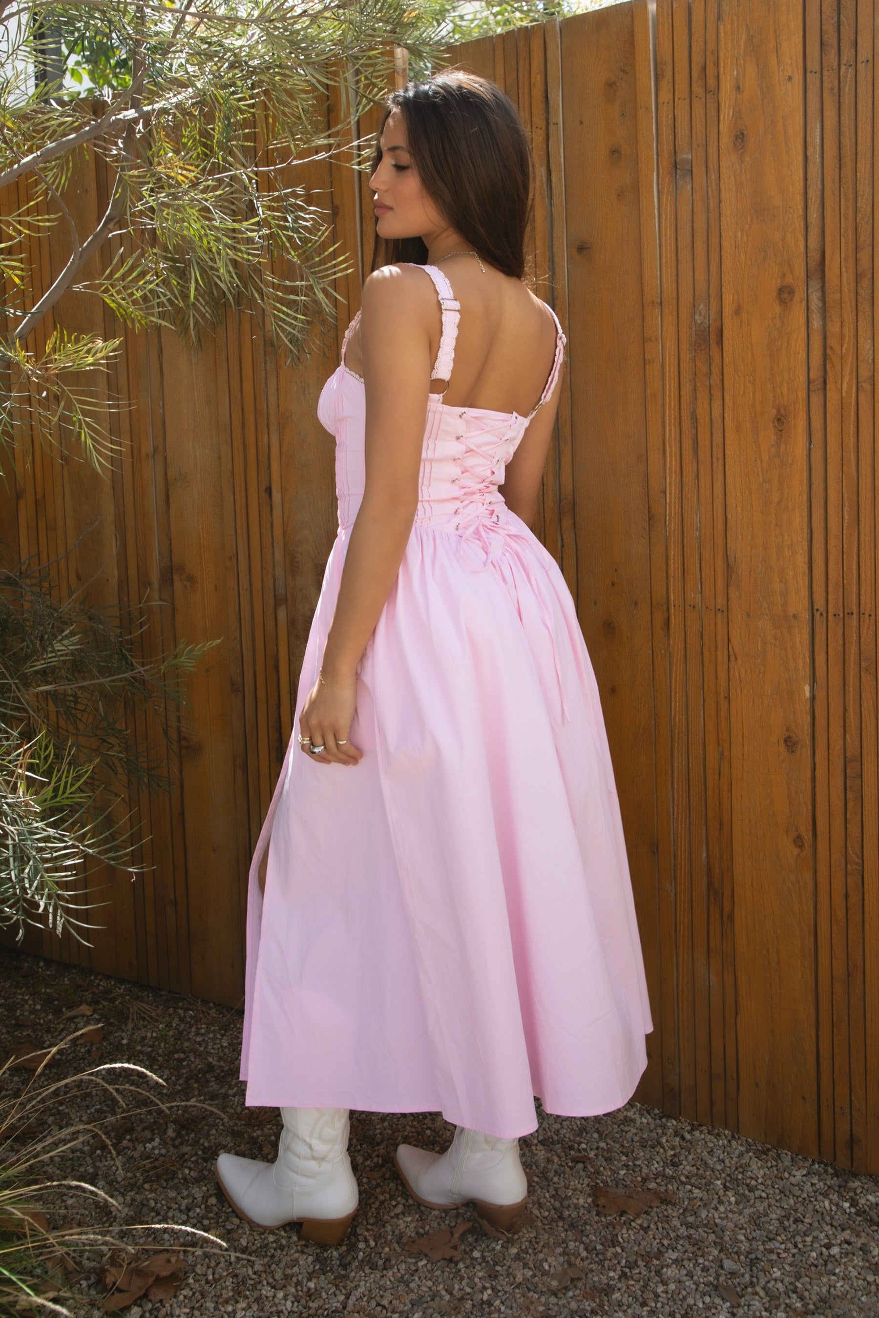 Woman wearing TIC TOC DA31086-LORETTA LORETTA stretch poplin maxi dress featuring adjustable lace shoulder straps, a cinched bust with bow detail, lace overlay corset-style bodice with vertical seaming, lace-up back and hidden side zipper, and a gathered A-line maxi skirt with a shaped waist and V-cut hip seam, styled for a romantic spring/summer occasion look.