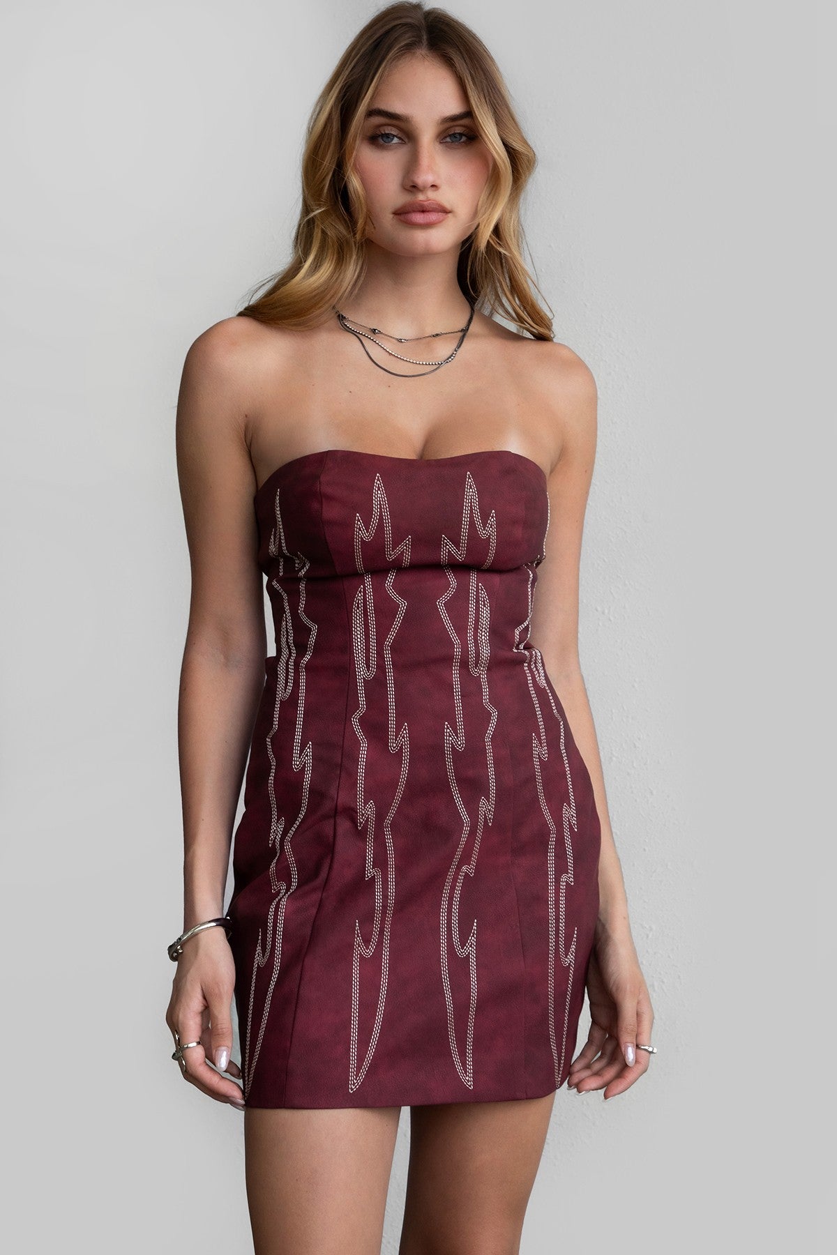 TIC TOC DA30447 ARIZONA Embroidered Western Mini Dress. A strapless PU vegan leather mini dress with a sweetheart neckline, open back lace-up tie, and Western-inspired embroidery.