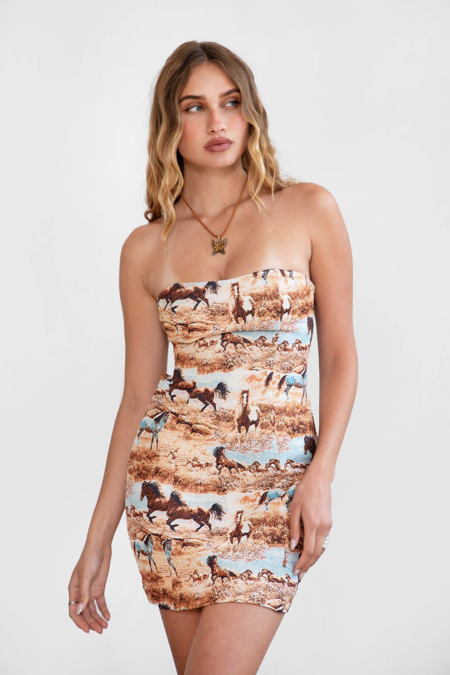 Woman wearing a strapless dress with horse print on a white background
