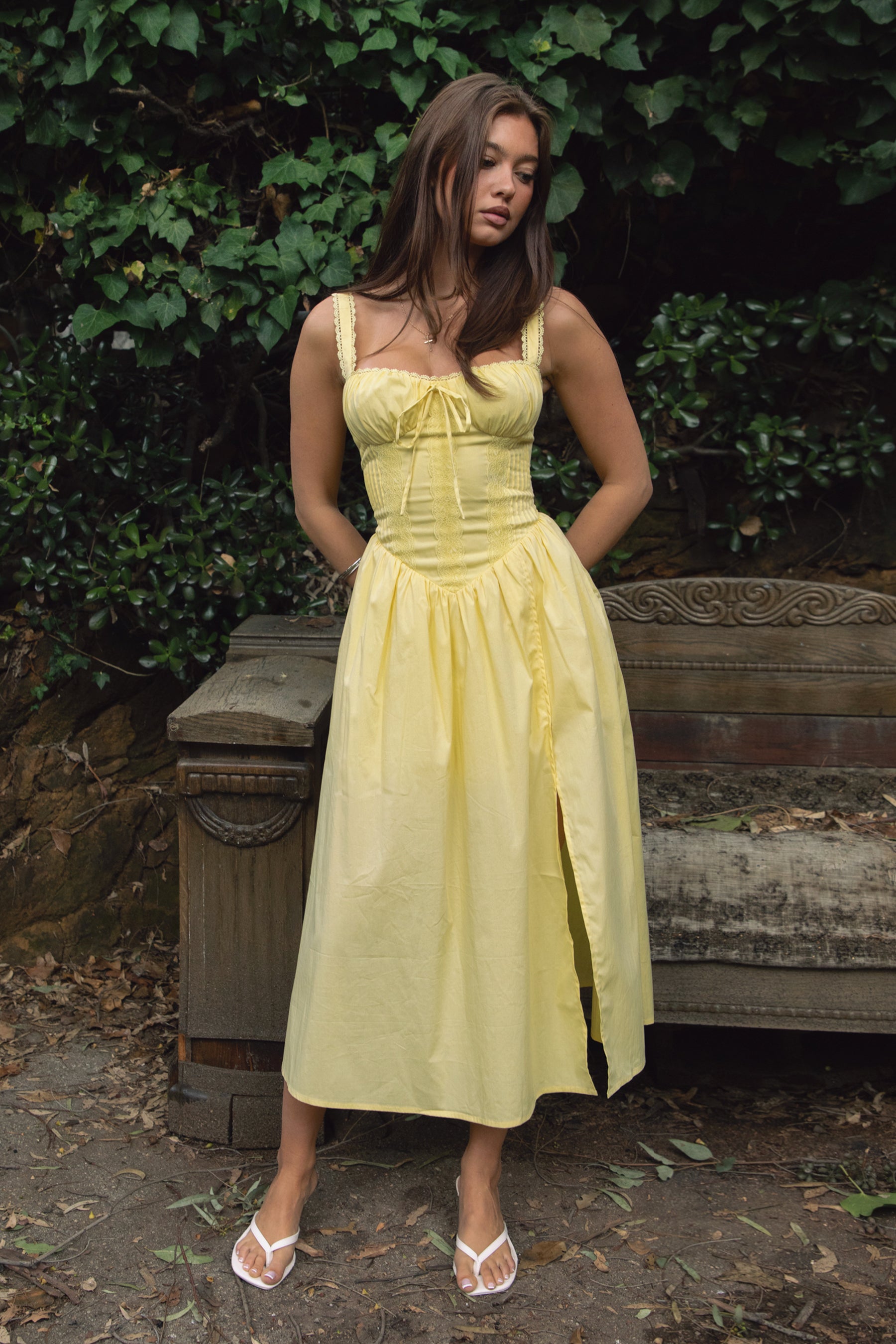 Woman wearing TIC TOC DA31086-LORETTA LORETTA stretch poplin maxi dress featuring adjustable lace shoulder straps, a cinched bust with bow detail, lace overlay corset-style bodice with vertical seaming, lace-up back and hidden side zipper, and a gathered A-line maxi skirt with a shaped waist and V-cut hip seam, styled for a romantic spring/summer occasion look.