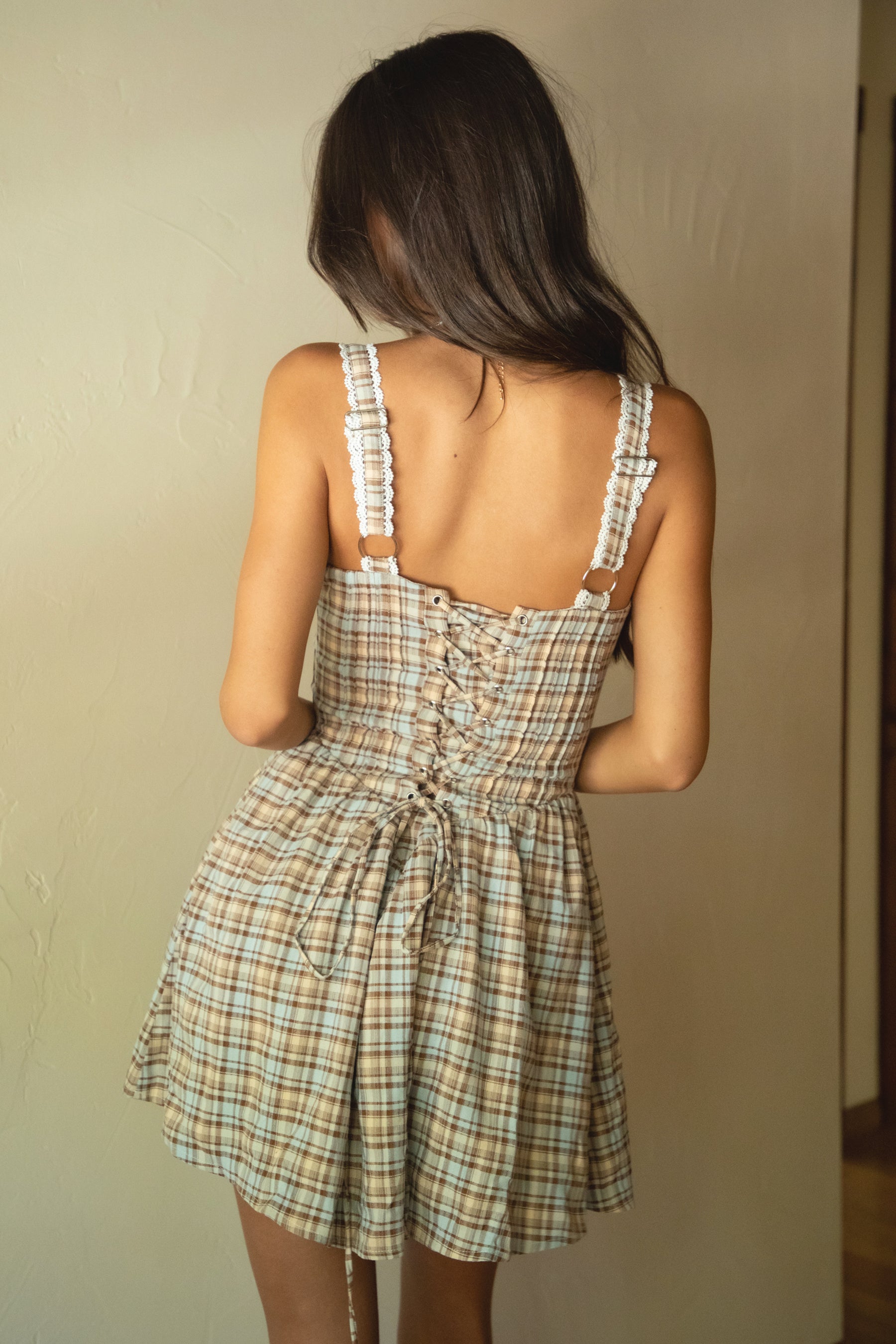 Woman wearing a plaid dress with a neutral background