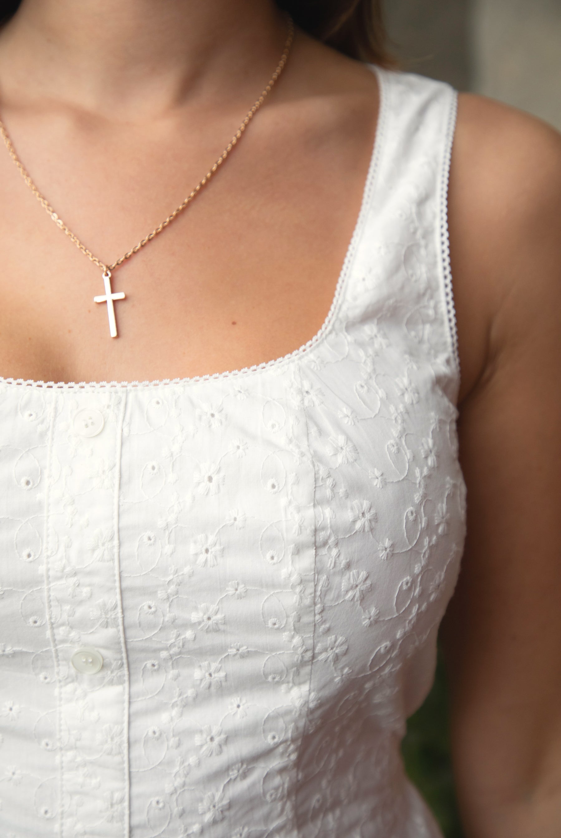 Woman wearing TIC TOC DA31929-AMAYRA AMAYRA eyelet mini dress made from allover eyelet embroidered cotton fabric, featuring a sleeveless square neckline, faux button front detail, fitted bodice with clean seams, adjustable back waist tie, hidden back zipper, and scalloped eyelet lace hemline, styled for a brunch-ready garden party look.