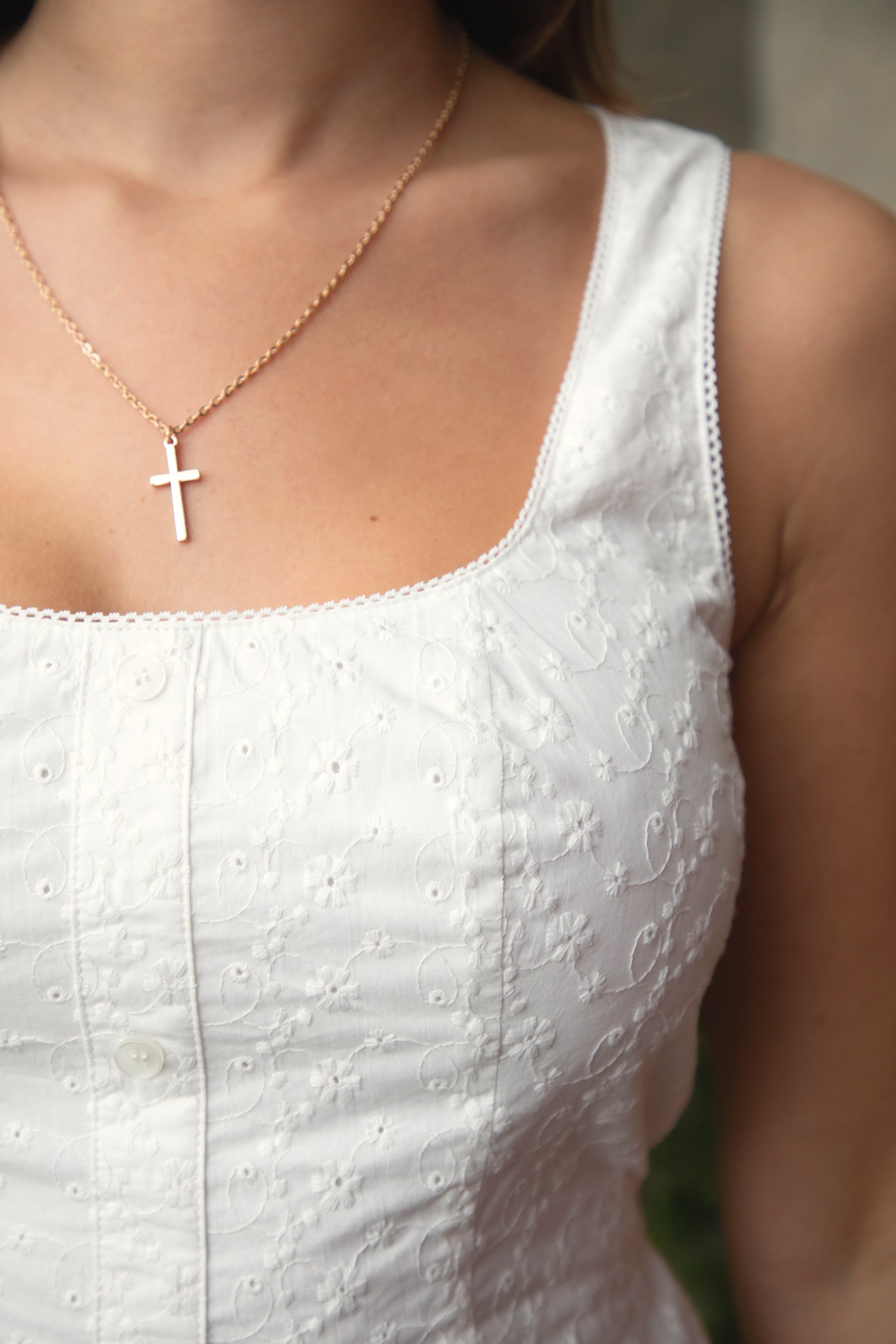 Woman wearing TIC TOC DA31929-AMAYRA AMAYRA eyelet mini dress made from allover eyelet embroidered cotton fabric, featuring a sleeveless square neckline, faux button front detail, fitted bodice with clean seams, adjustable back waist tie, hidden back zipper, and scalloped eyelet lace hemline, styled for a brunch-ready garden party look.