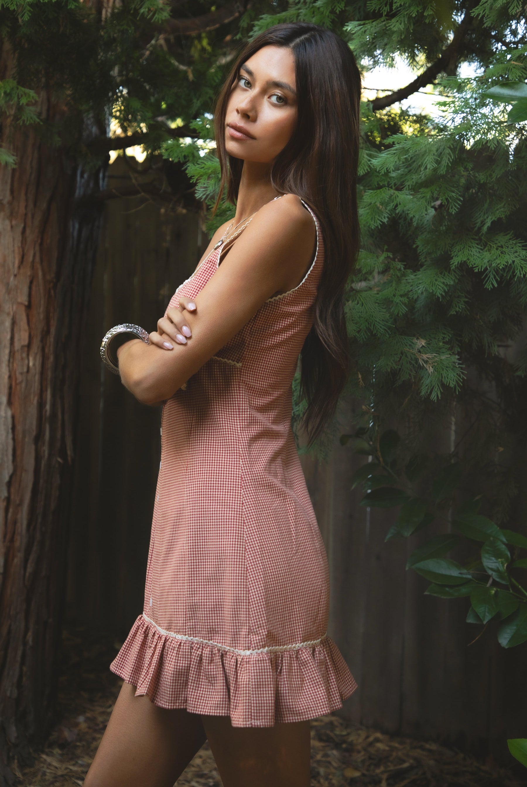 Woman wearing TIC TOC DA31931-AMELIE AMELIE gingham mini dress featuring a square scoop neckline with picot trim, wide shoulder straps, front faux button detail, fitted bodice with under bust seam, ruffled hem mini skirt in gingham poplin fabric, and a clean back zipper closure, styled with simple accessories for a coquette, western-sweet summer look.