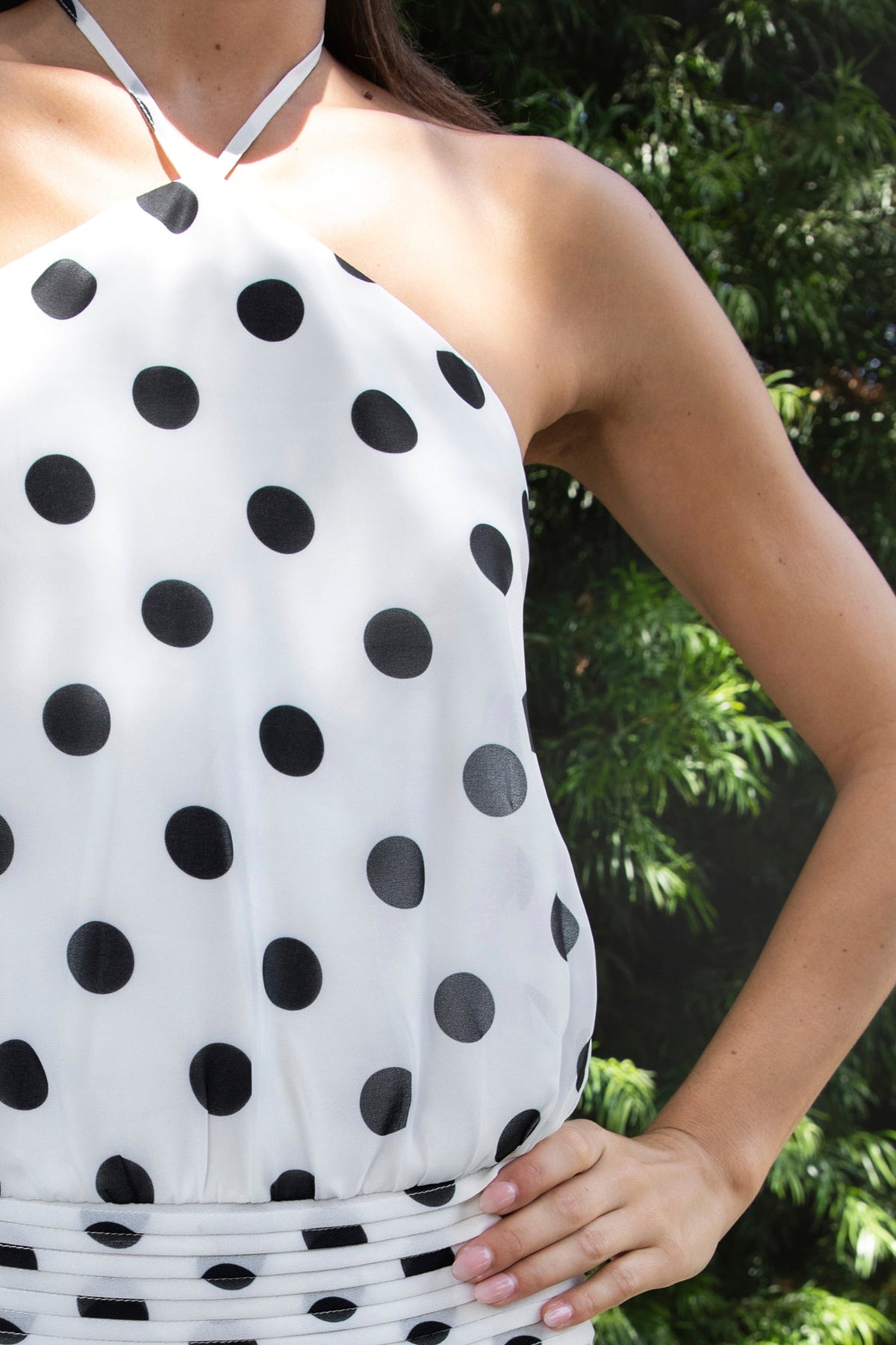 Woman wearing BIJOO polka dot chiffon halter mini dress featuring flowy chiffon fabric, bold polka dot print, adjustable self tie halter neckline, open back silhouette, relaxed blouson bodice, ruched waistband detailing, layered flared mini skirt, and fully lined construction for comfortable coverage.