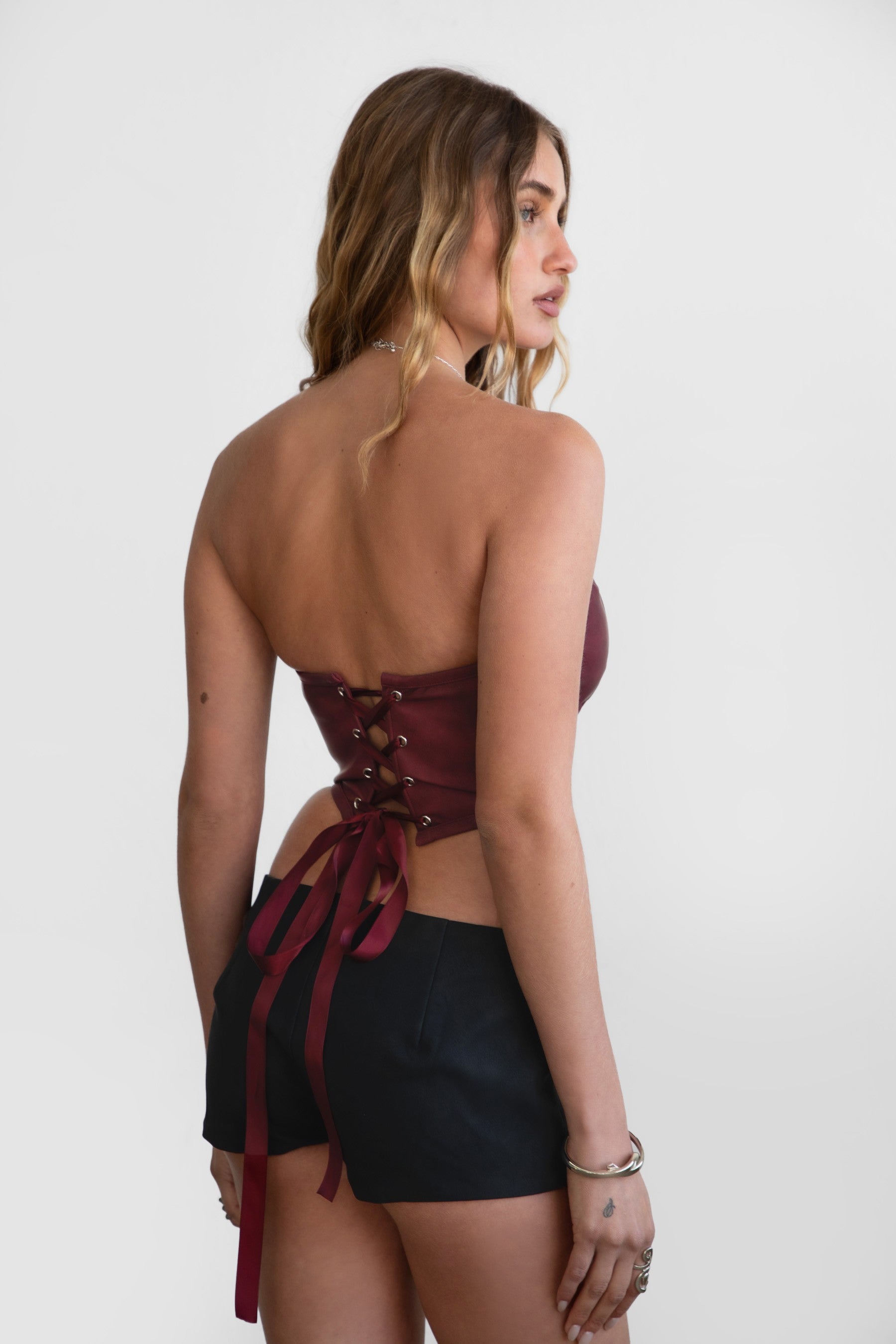 Model wearing LEIAH vegan leather micro shorts in black and brown, styled for a Western festival look