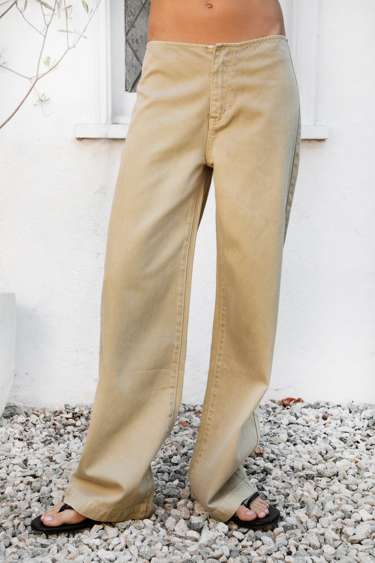 Woman wearing BOWDEN washed low rise wide leg denim pants featuring 100% cotton denim, relaxed vintage inspired silhouette, low rise waist, loose wide leg design, soft lived in washed finish, clean front styling, front zipper fly closure, classic back patch pockets, and full length fit.
