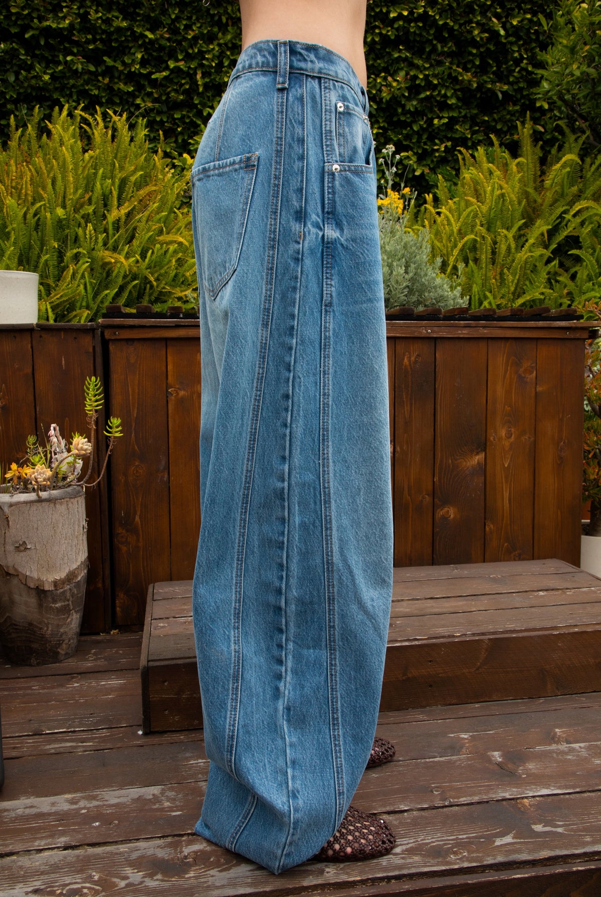 Woman wearing ROMII mid rise baggy fit barrel jeans featuring soft cotton lyocell denim, relaxed barrel leg silhouette, panel seam detailing, subtle knee tucks, classic five pocket design, zip fly, and button closure for modern casual streetwear styling.
