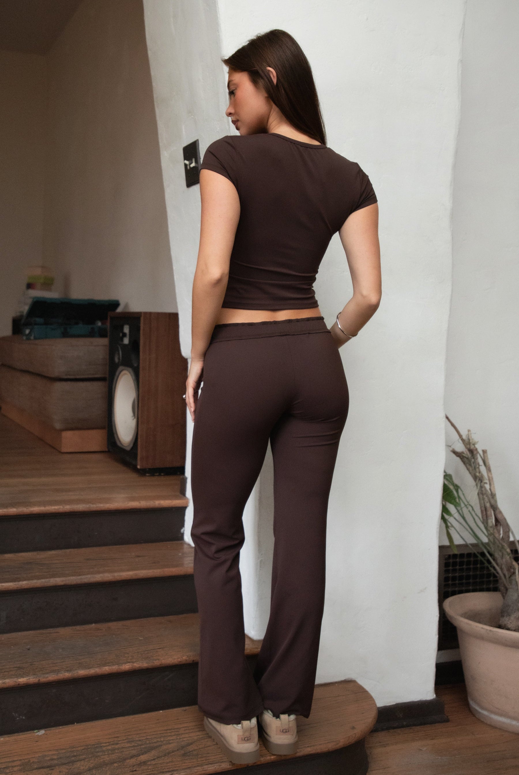 Woman wearing TIC TOC PH31905BA-NYLEE-WL navy NYLEE WL wide leg pants made from soft span jersey fabric, featuring a high-stretch body-hugging fit through the hips, foldover waistband with tie detail, and full-length wide leg silhouette, styled indoors with a matching top for a coordinated lounge/athleisure look.