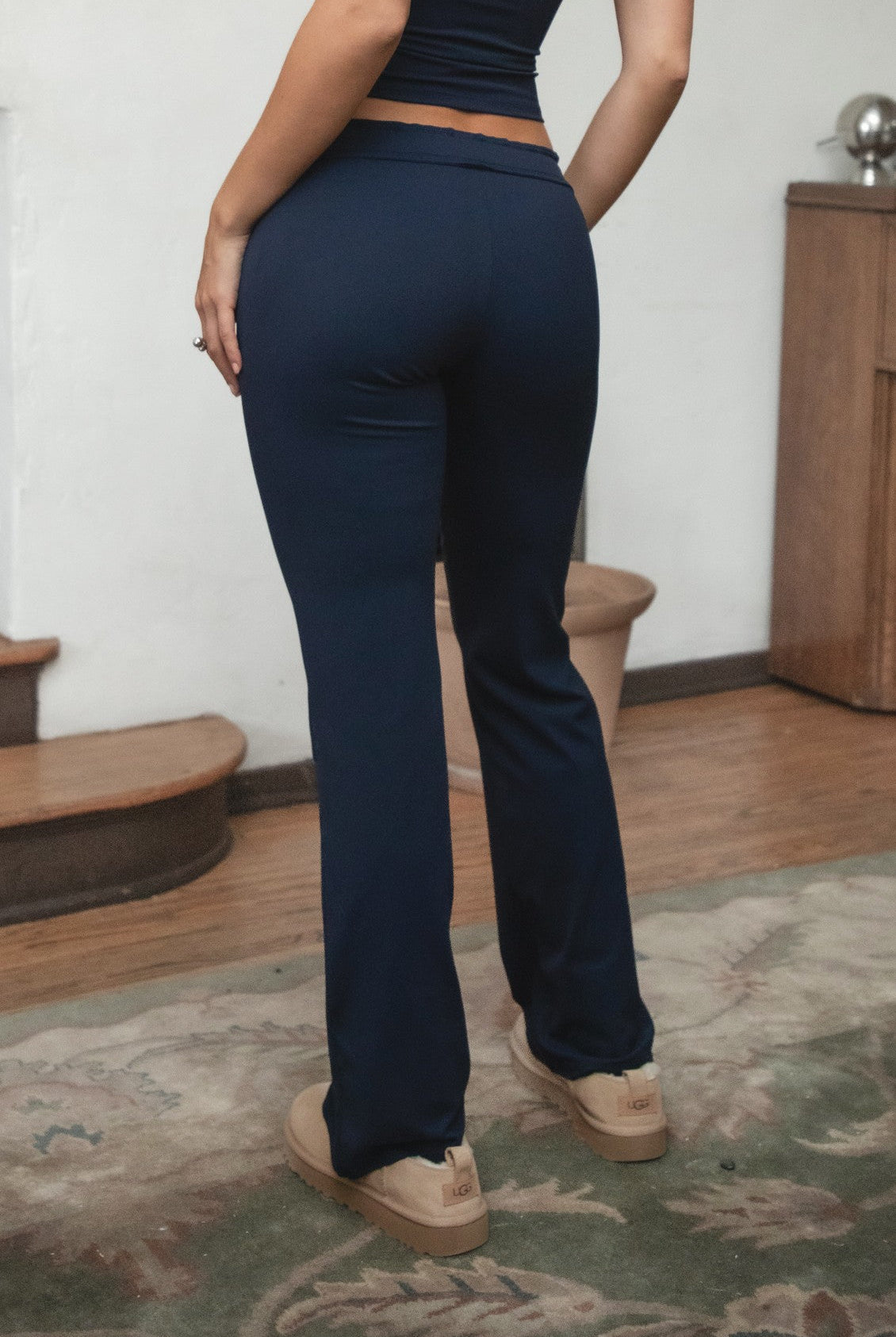 Woman wearing TIC TOC PH31905BA-NYLEE-WL navy NYLEE WL wide leg pants made from soft span jersey fabric, featuring a high-stretch body-hugging fit through the hips, foldover waistband with tie detail, and full-length wide leg silhouette, styled indoors with a matching top for a coordinated lounge/athleisure look.