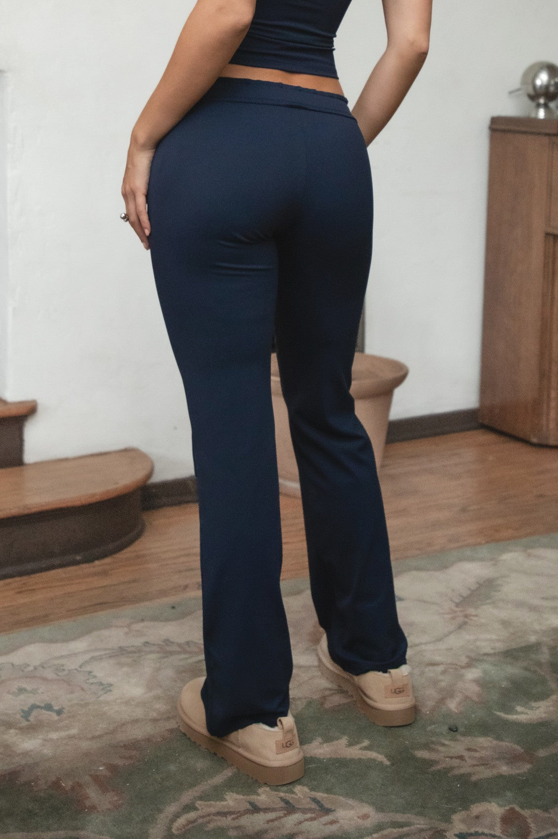 Woman wearing TIC TOC PH31905BA-NYLEE-WL navy NYLEE WL wide leg pants made from soft span jersey fabric, featuring a high-stretch body-hugging fit through the hips, foldover waistband with tie detail, and full-length wide leg silhouette, styled indoors with a matching top for a coordinated lounge/athleisure look.