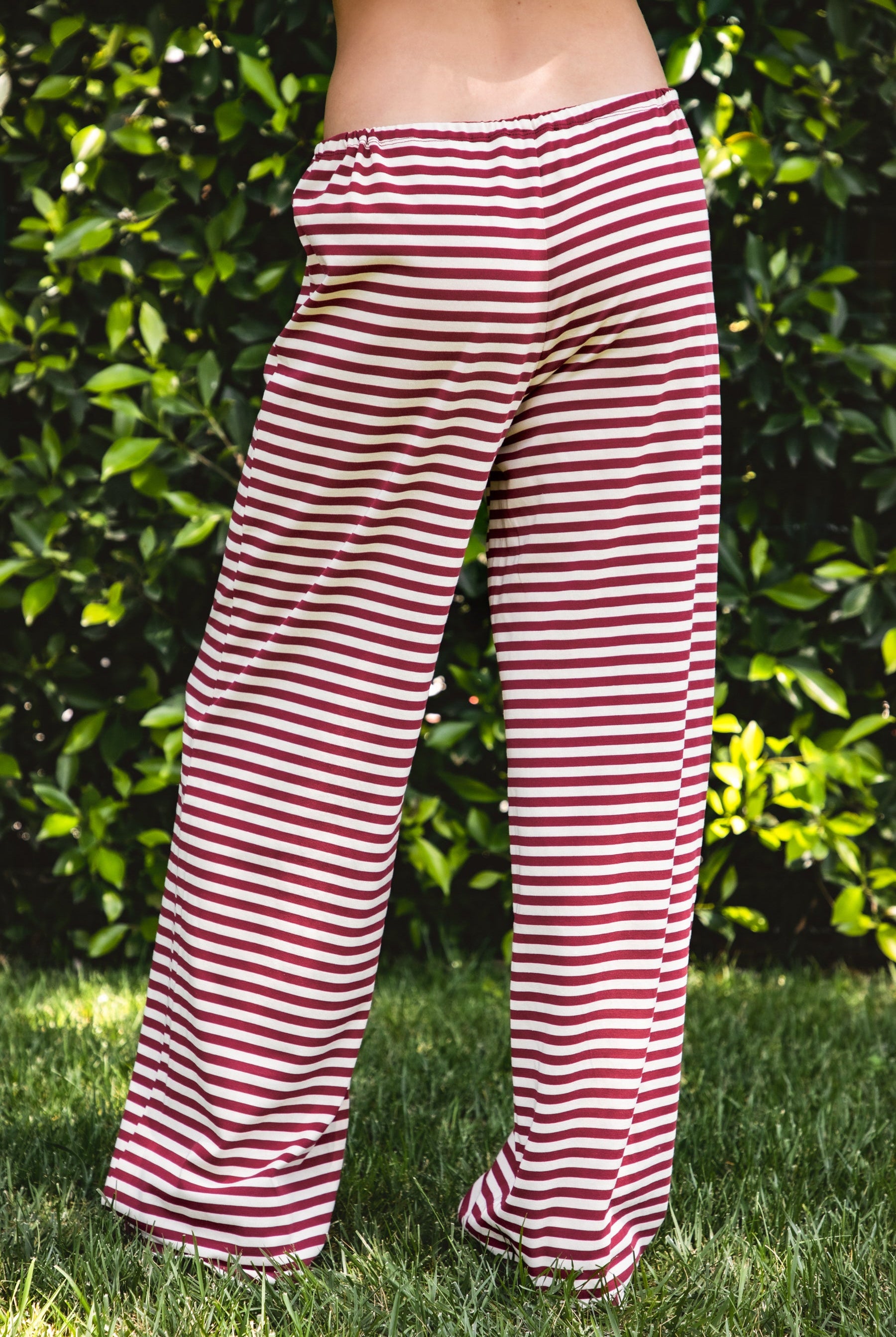 Woman wearing MARLOWE stretch mid waist stripe wide leg pants featuring an allover stripe pattern, adjustable drawstring waist, relaxed wide leg silhouette, full length fit, and soft stretch jersey fabric for cozy casual lounge styling.