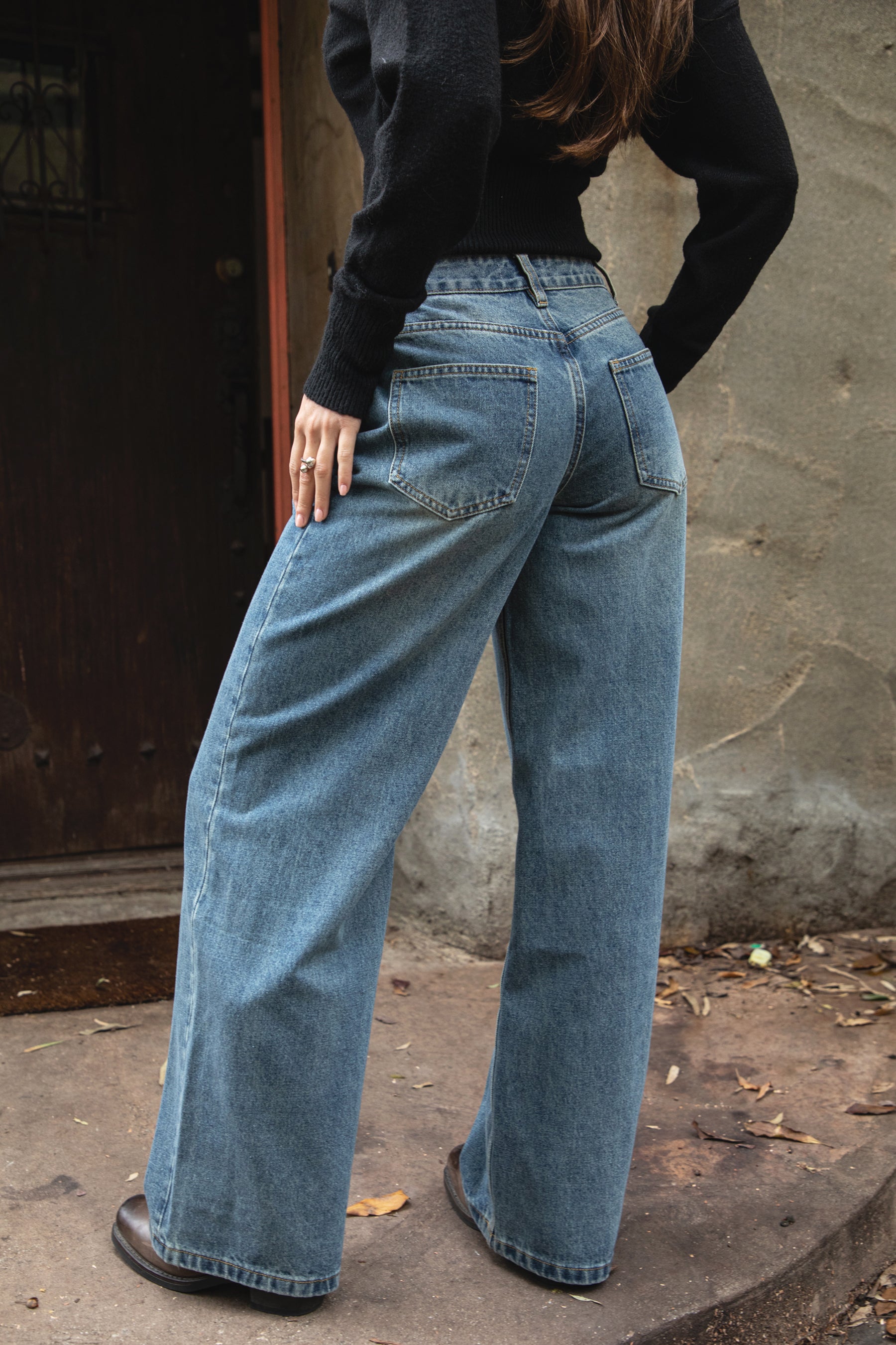 Woman wearing TIC TOC PJ31550-WINSLEY WINSLEY low rise straight leg denim jeans in a vintage blue wash with light fading, featuring a long straight wide leg silhouette, classic 5-pocket styling, belt loops, and a zipper fly button closure, styled casually with a fitted top for an everyday denim look.