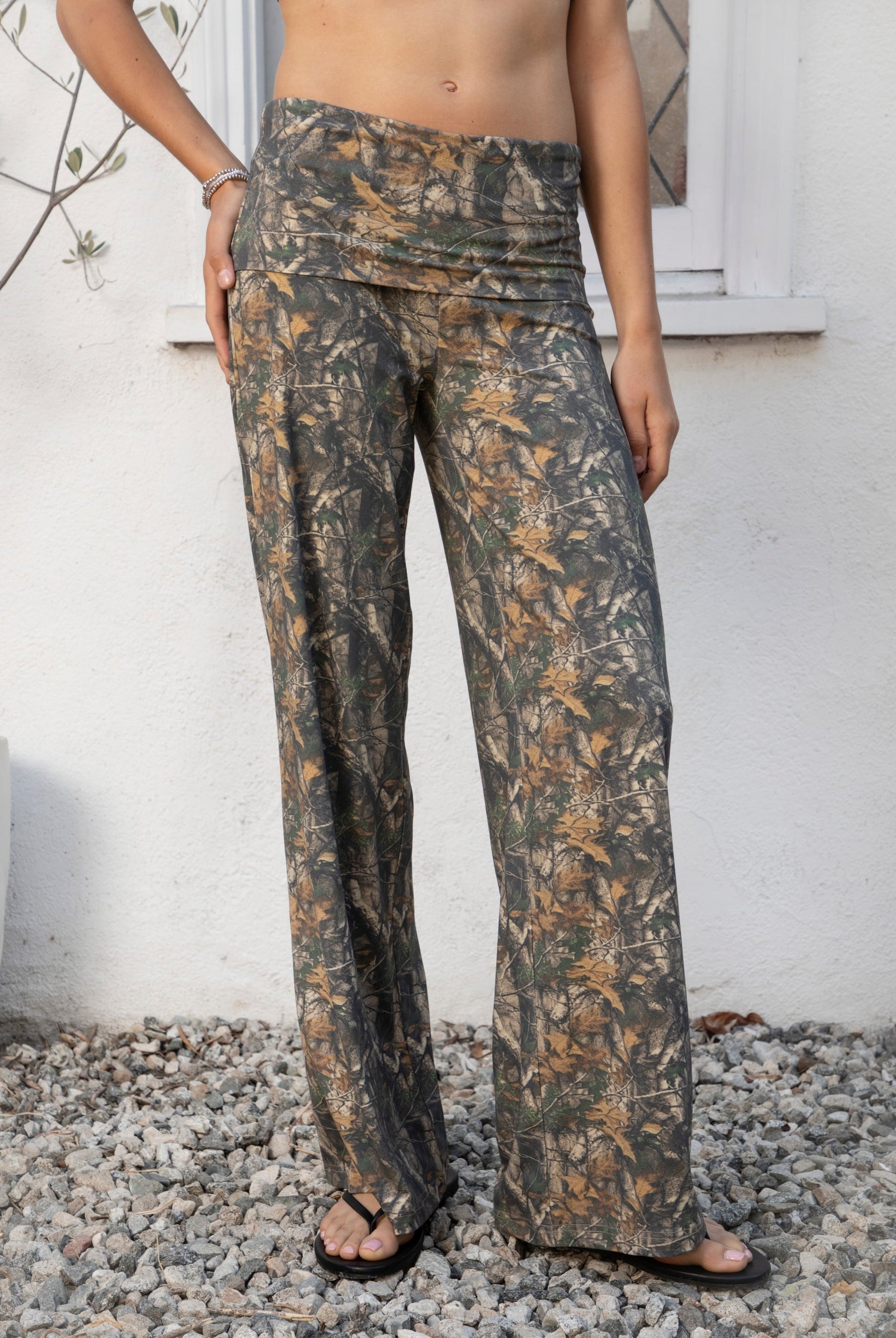 Woman wearing BAYOU dark woodland camo stretch foldover wide leg leggings featuring soft brushed stretch jersey fabric, allover woodland camo print, adjustable foldover waistband, relaxed wide leg silhouette, and four way stretch fabric designed for everyday comfort and easy movement.