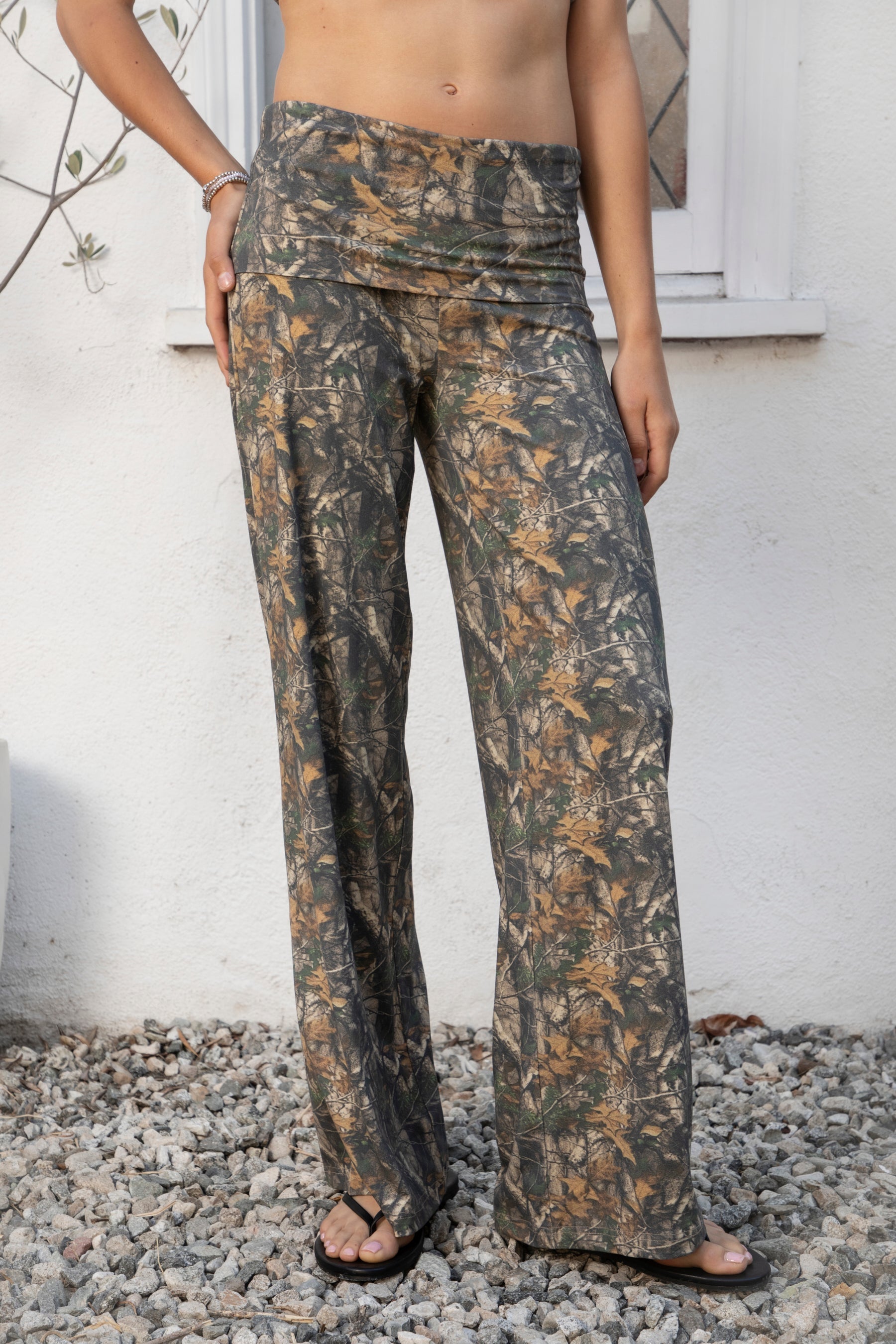 Woman wearing BAYOU dark woodland camo stretch foldover wide leg leggings featuring soft brushed stretch jersey fabric, allover woodland camo print, adjustable foldover waistband, relaxed wide leg silhouette, and four way stretch fabric designed for everyday comfort and easy movement.