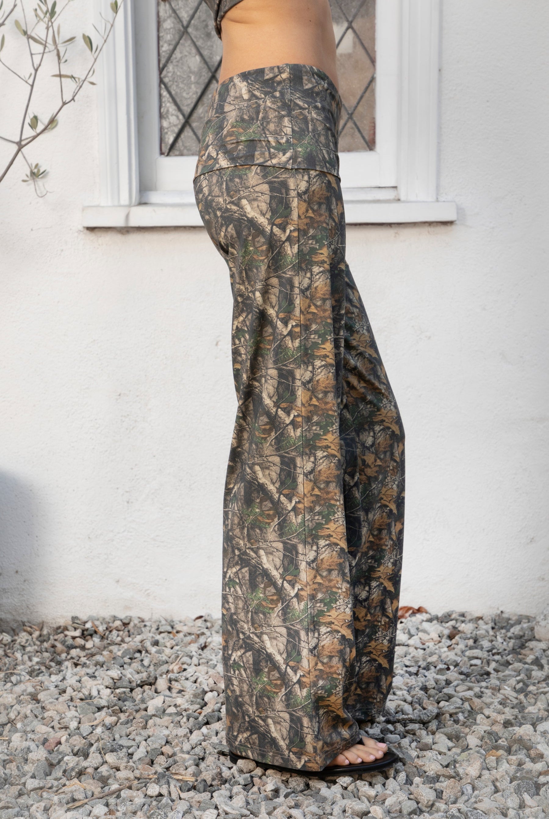 Woman wearing BAYOU dark woodland camo stretch foldover wide leg leggings featuring soft brushed stretch jersey fabric, allover woodland camo print, adjustable foldover waistband, relaxed wide leg silhouette, and four way stretch fabric designed for everyday comfort and easy movement.