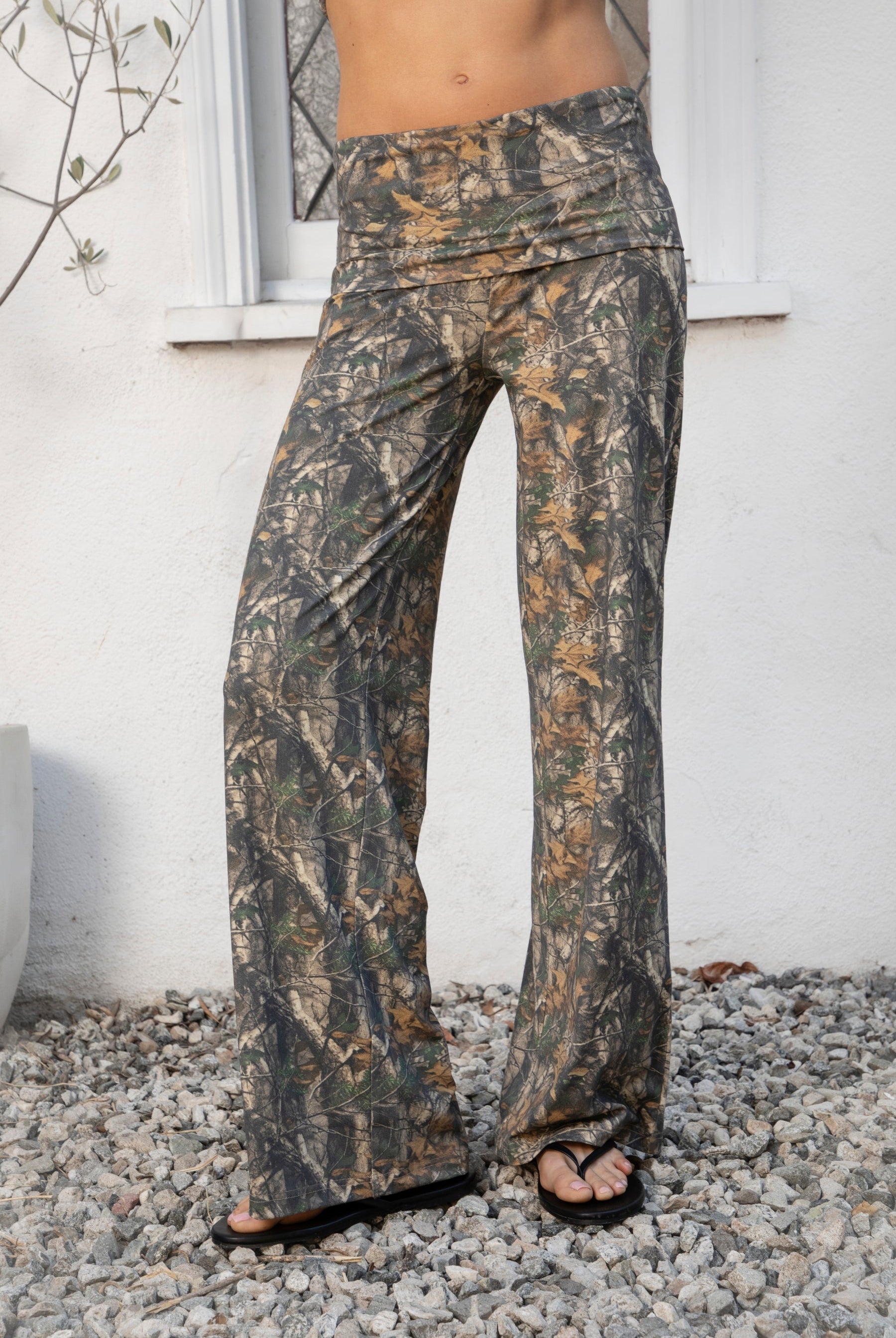 Woman wearing BAYOU dark woodland camo stretch foldover wide leg leggings featuring soft brushed stretch jersey fabric, allover woodland camo print, adjustable foldover waistband, relaxed wide leg silhouette, and four way stretch fabric designed for everyday comfort and easy movement.