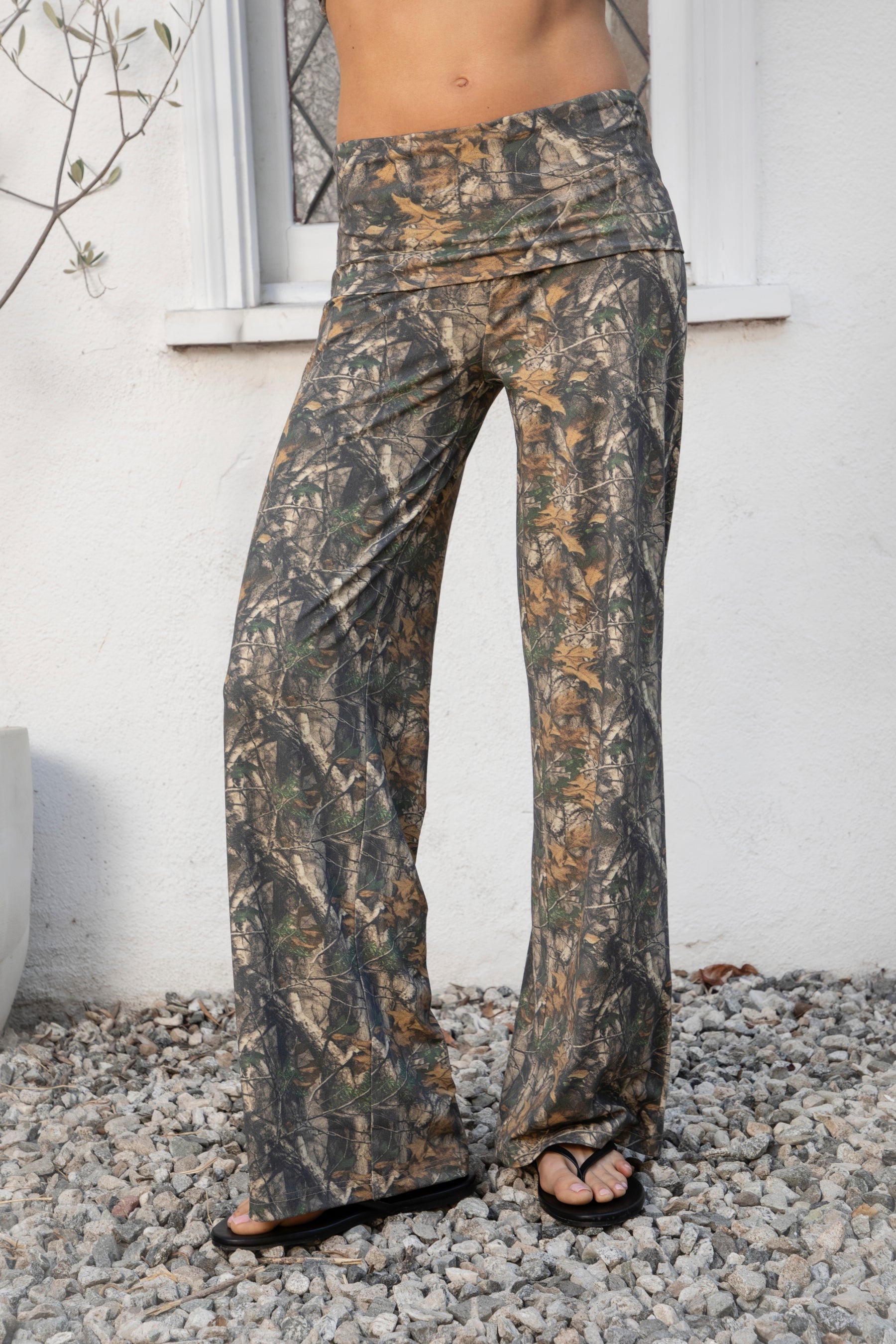 Woman wearing BAYOU dark woodland camo stretch foldover wide leg leggings featuring soft brushed stretch jersey fabric, allover woodland camo print, adjustable foldover waistband, relaxed wide leg silhouette, and four way stretch fabric designed for everyday comfort and easy movement.