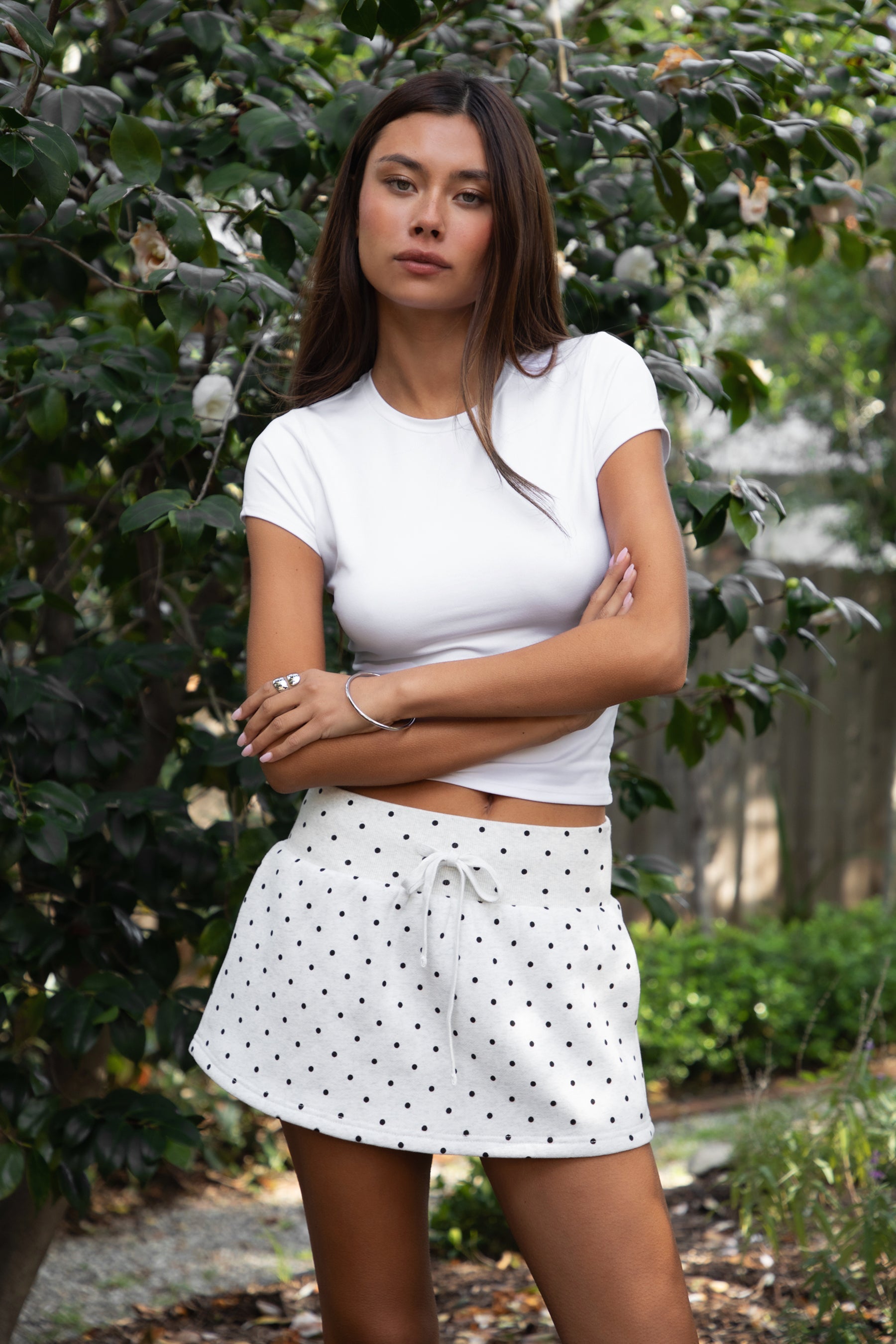 Woman wearing TIC TOC SH31896 JOTTIE plush fleece polka dot mini skort featuring an allover polka dot print, mid-rise elastic waistband with adjustable drawstring, built-in shorts, and side pockets for a cozy sporty casual look.