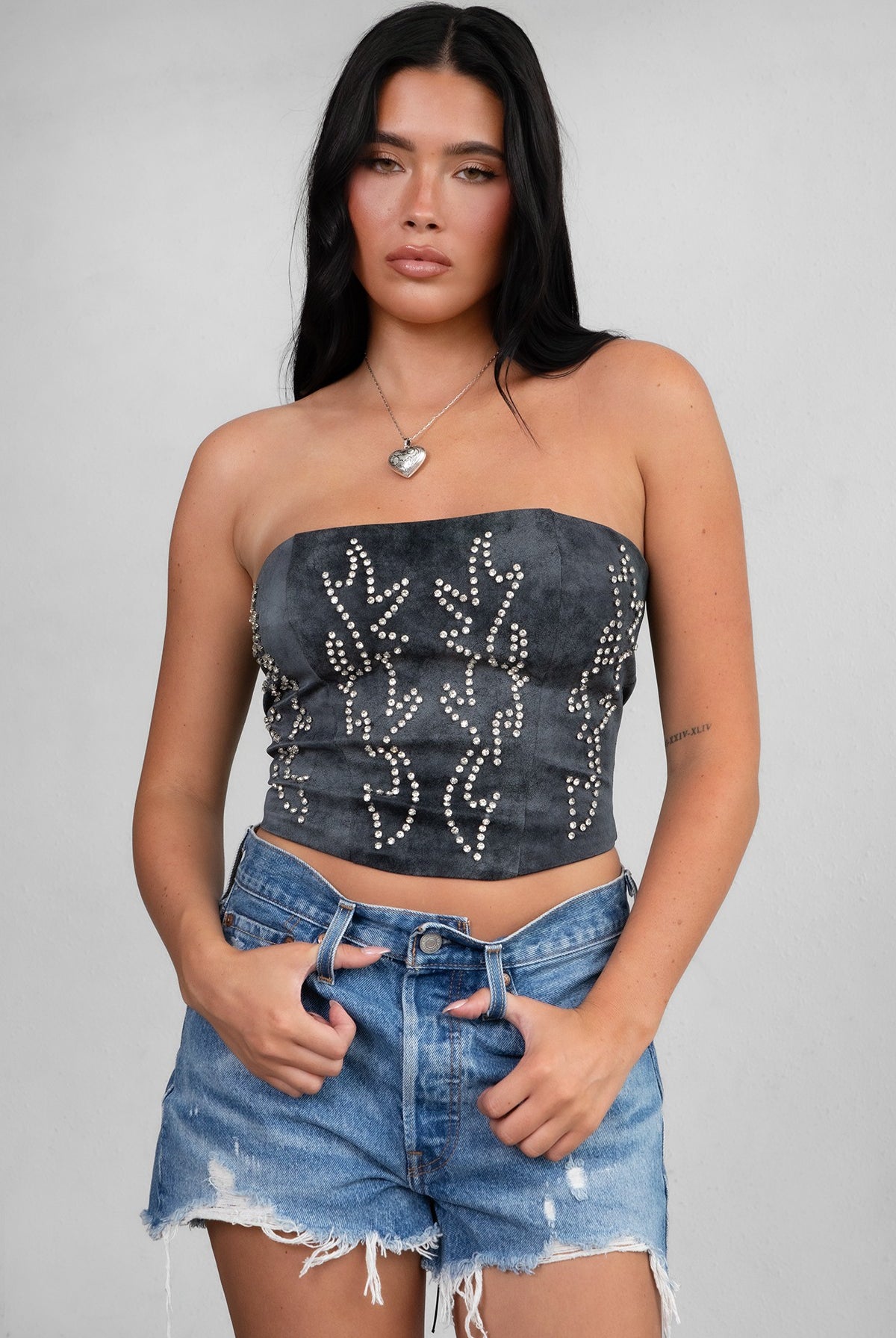 TIC TOC TA29069 BECKEE PU Vegan Leather Corset Top in distressed leather. Features a straight strapless neckline, rhinestone western detail, and lace-up back in color black.