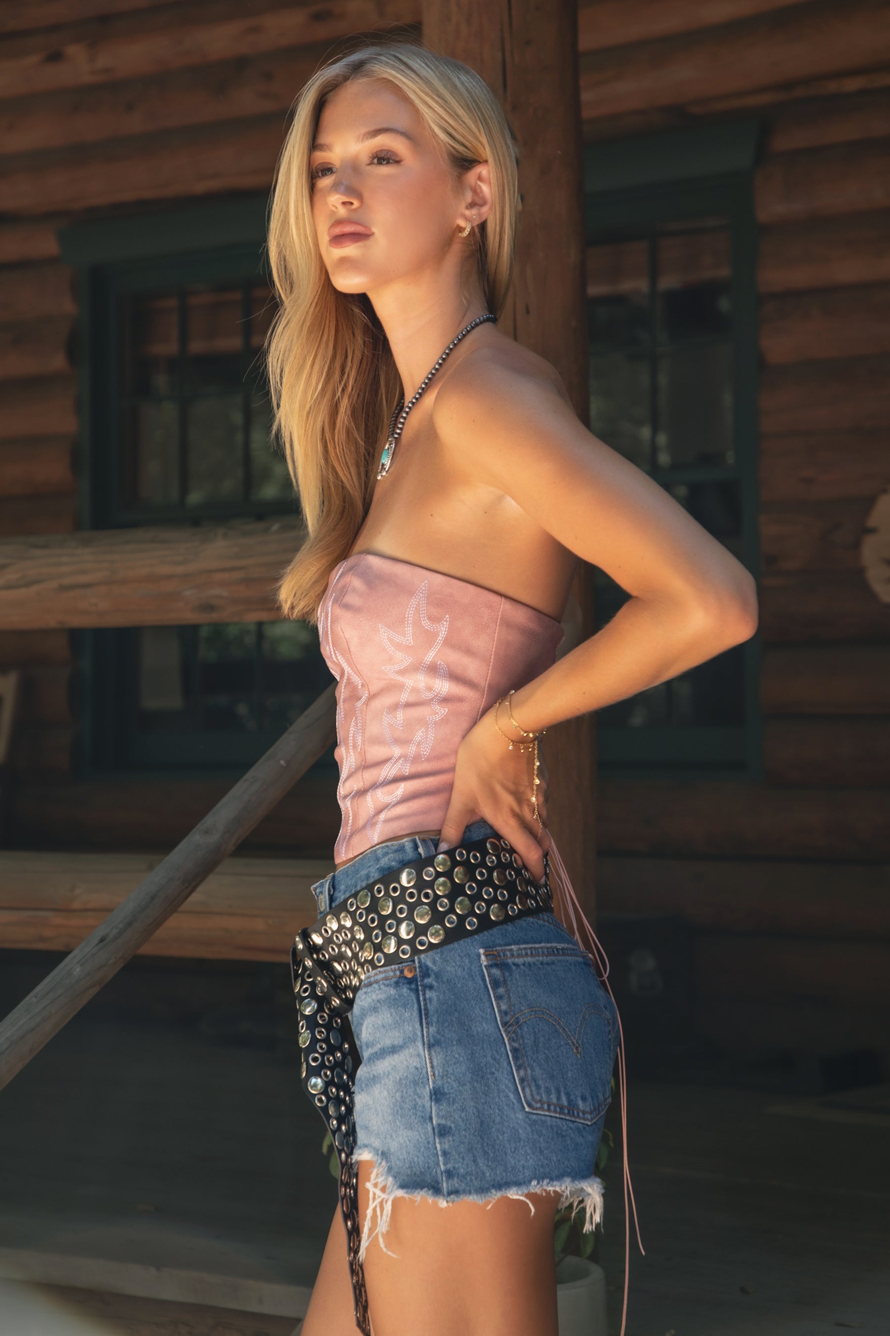 Woman wearing TIC TOC TA29069-BECKEE BECKEE embroidered western corset top featuring a strapless straight neckline, boned panel construction, dual lined PU vegan leather body, and rope lace-up detail at the center back, styled with high-waisted denim for a bold rodeo-ready western going-out look.