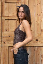 Woman wearing a western embroidered brown suede top and dark pants against a wooden background