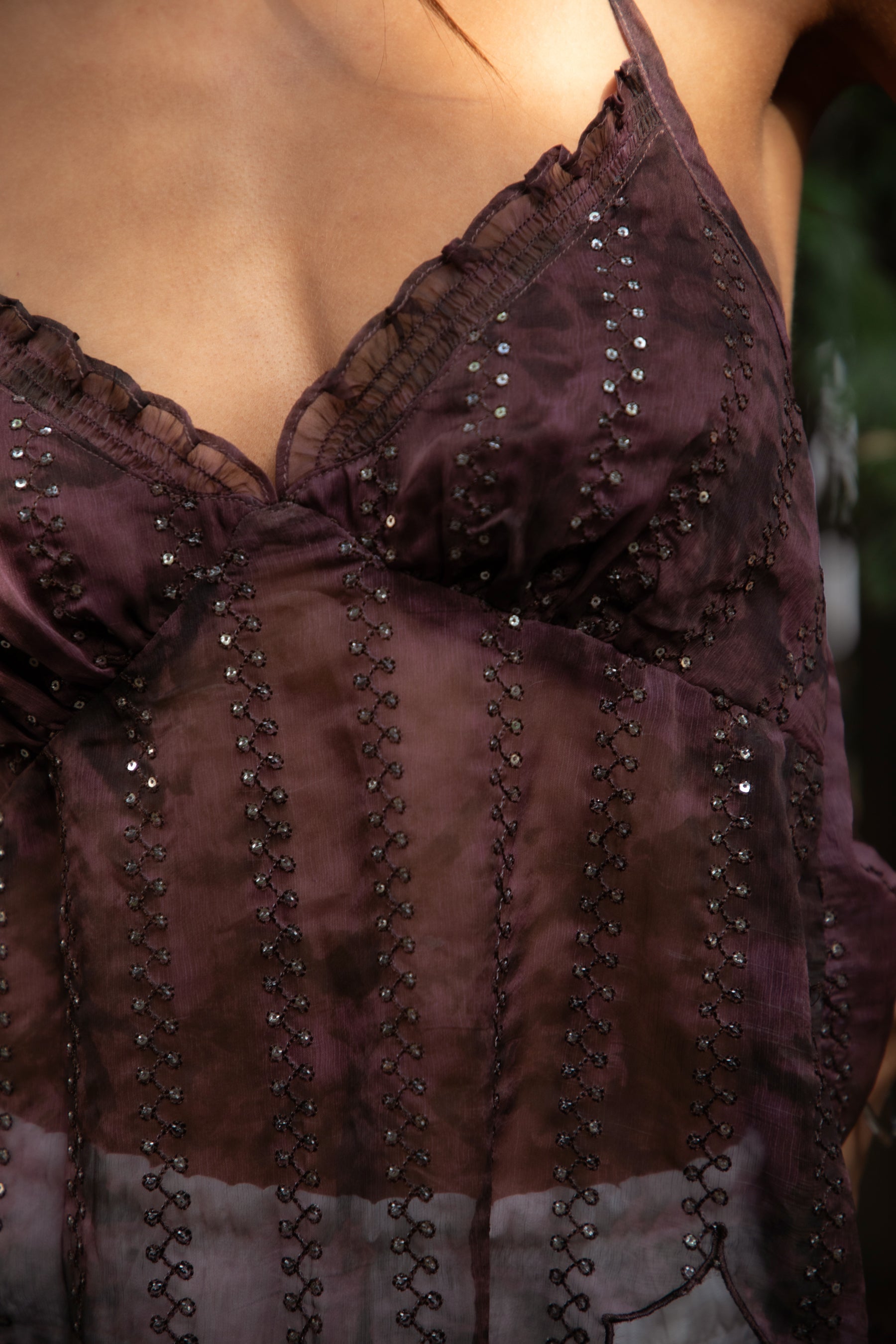 Woman wearing TIC TOC TA31758 ISOLA scalloped sequin chiffon open back halter top featuring a ruffle-trim V-neckline, delicate sequin embroidered chiffon, adjustable self-tie halter neck, open back tie closure, and a scalloped handkerchief hem, styled for a romantic vacation and elevated western evening look.