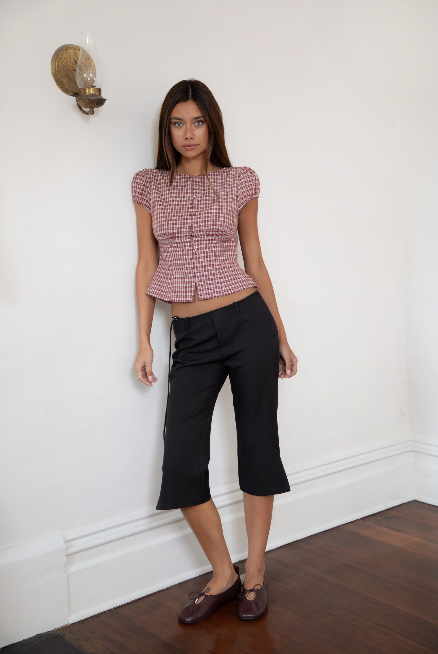 Woman wearing TIC TOC TA32072 DARIS gingham puff sleeve blouse top featuring soft cotton gingham fabric with a classic check pattern, cropped feminine fit, round neckline with front button closure, puff short sleeves, smocked back panel, and under bust smocking for a vintage-inspired western look.