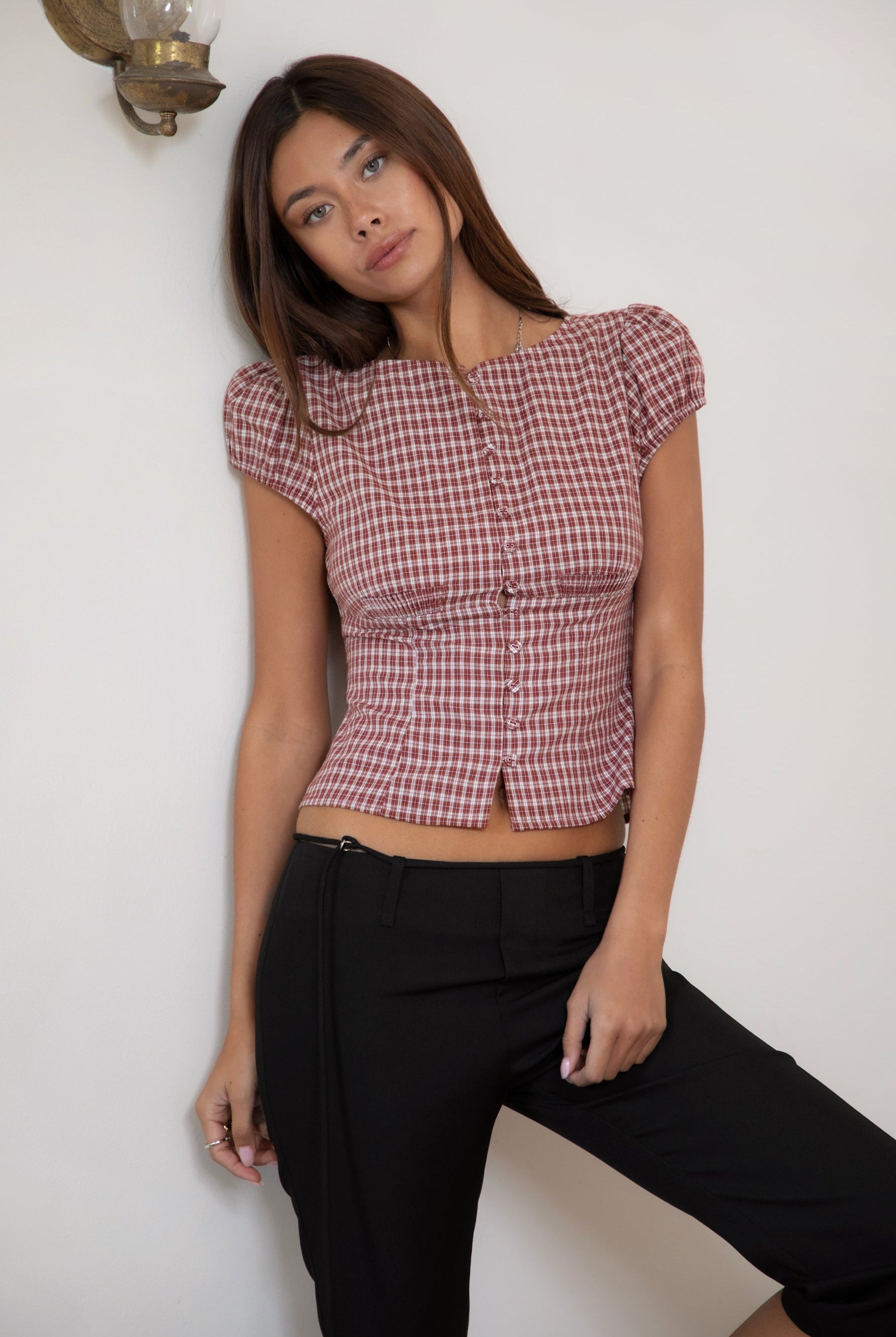 Woman wearing TIC TOC TA32072 DARIS gingham puff sleeve blouse top featuring soft cotton gingham fabric with a classic check pattern, cropped feminine fit, round neckline with front button closure, puff short sleeves, smocked back panel, and under bust smocking for a vintage-inspired western look.