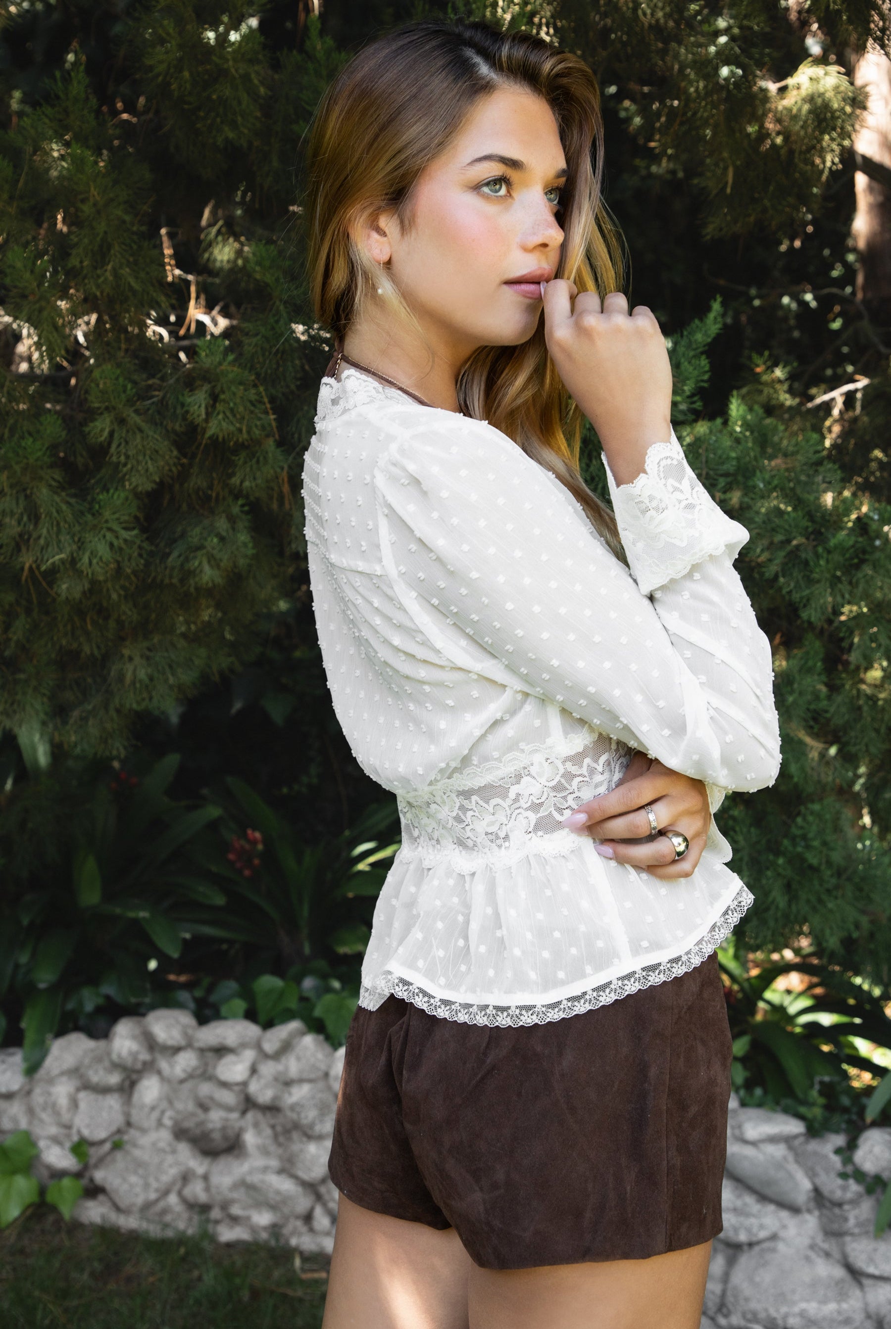 Woman wearing LACEWOOD polka dot chiffon lace long sleeve blouse top featuring sheer dotted chiffon fabric, scalloped lace trim along the V-neckline and cuffs, floral lace panel under the bust, flowy silhouette with flare hem, and front button closure for adjustable styling