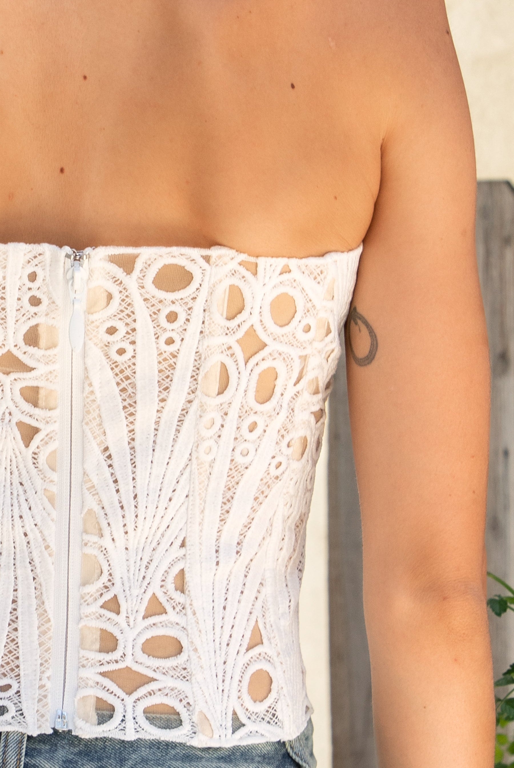 Woman wearing CALISTA crochet lace sheer corset top featuring delicate sheer crochet lace fabric, flattering scoop neckline, scalloped lace trim, lightweight layering design, soft curved hemline, and romantic boho styling for festivals, beach days, and resort getaways.