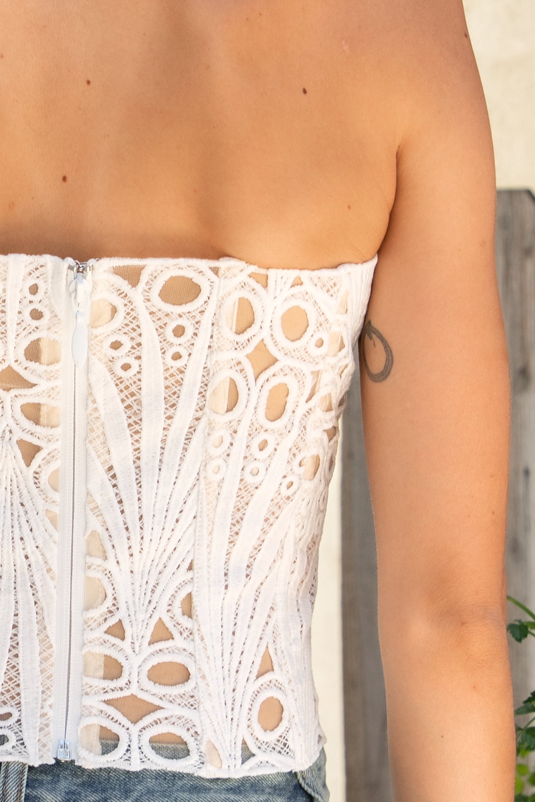 Woman wearing CALISTA crochet lace sheer corset top featuring delicate sheer crochet lace fabric, flattering scoop neckline, scalloped lace trim, lightweight layering design, soft curved hemline, and romantic boho styling for festivals, beach days, and resort getaways.