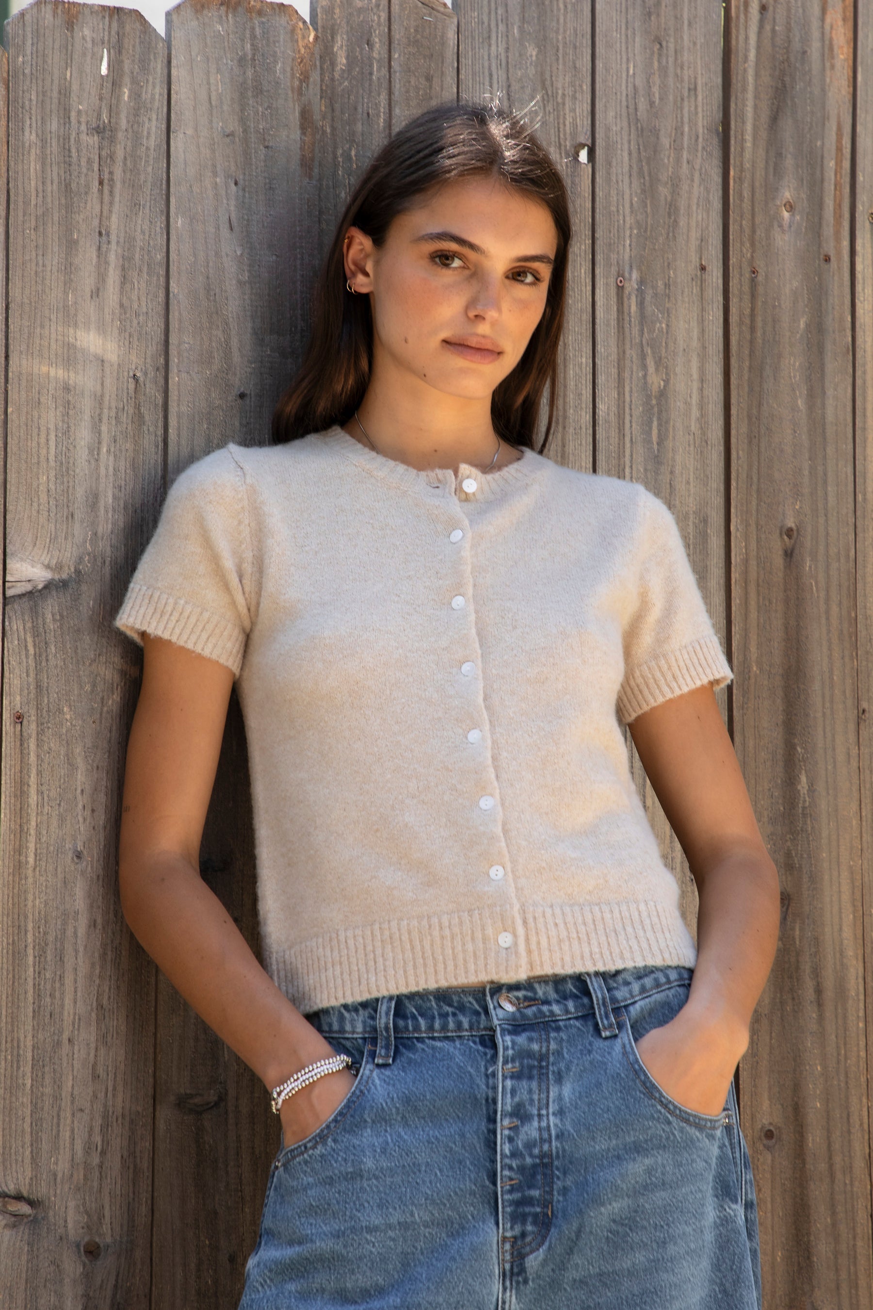 Woman wearing ADELE soft knit button short sleeve cardigan featuring plush sweater knit fabric, cozy comfortable feel, classic crew neckline, button front closure, short sleeves with ribbed cuffs and hem, and a relaxed yet flattering everyday fit for easy layering.