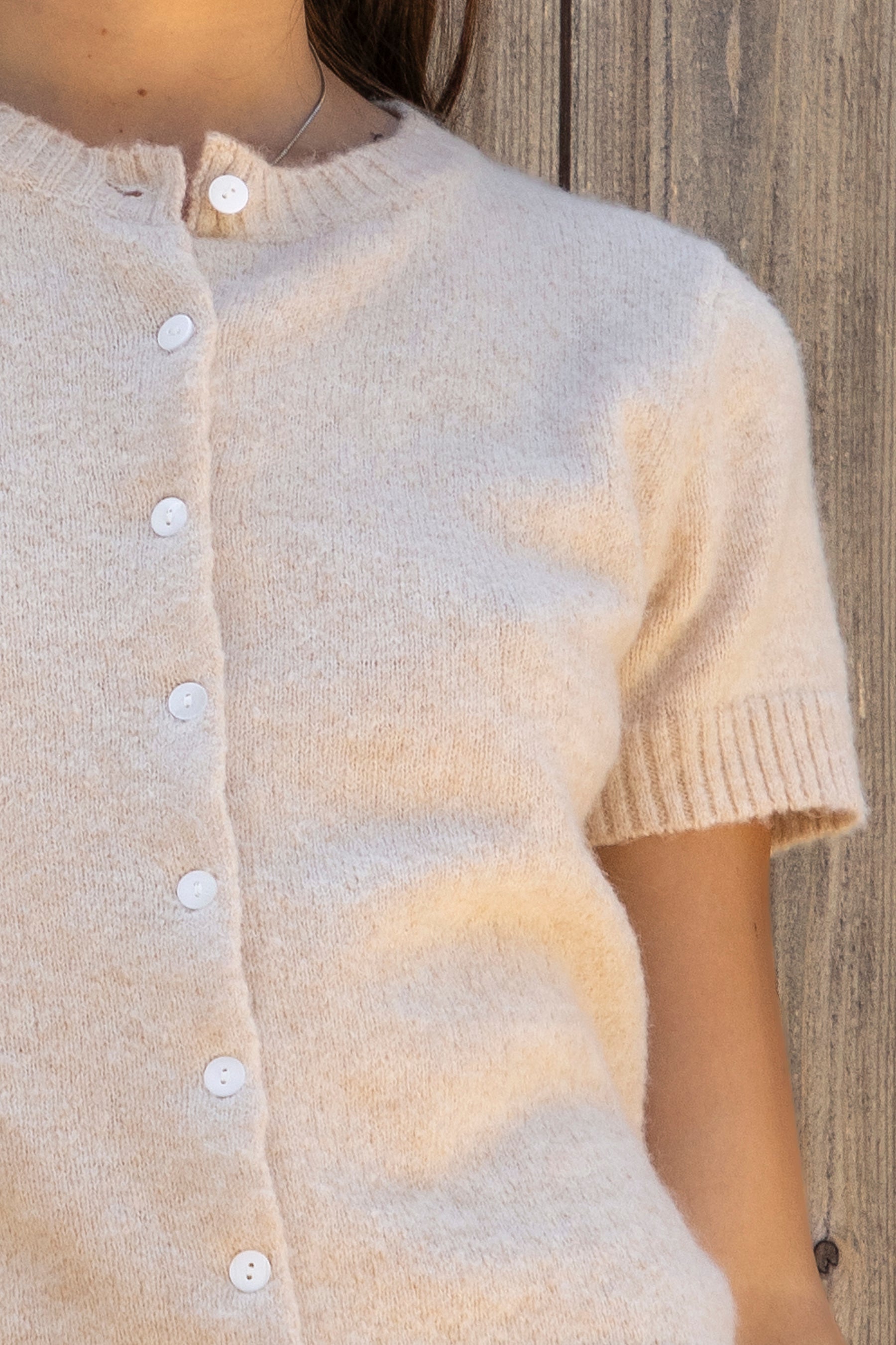Woman wearing ADELE soft knit button short sleeve cardigan featuring plush sweater knit fabric, cozy comfortable feel, classic crew neckline, button front closure, short sleeves with ribbed cuffs and hem, and a relaxed yet flattering everyday fit for easy layering.