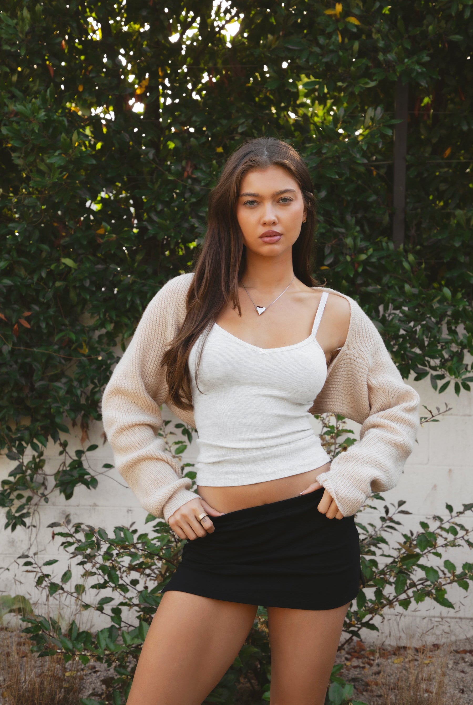 Woman wearing TIC TOC TC28065-FLUFF FLUFF shrug style crop cardigan bolero featuring an open front construction, easy semi loose fit, ultra cropped hem at the waist, and long semi loose sleeves finished with ribbed fitted cuffs, styled layered over a fitted tank and high-rise bottoms for a light, versatile everyday look.