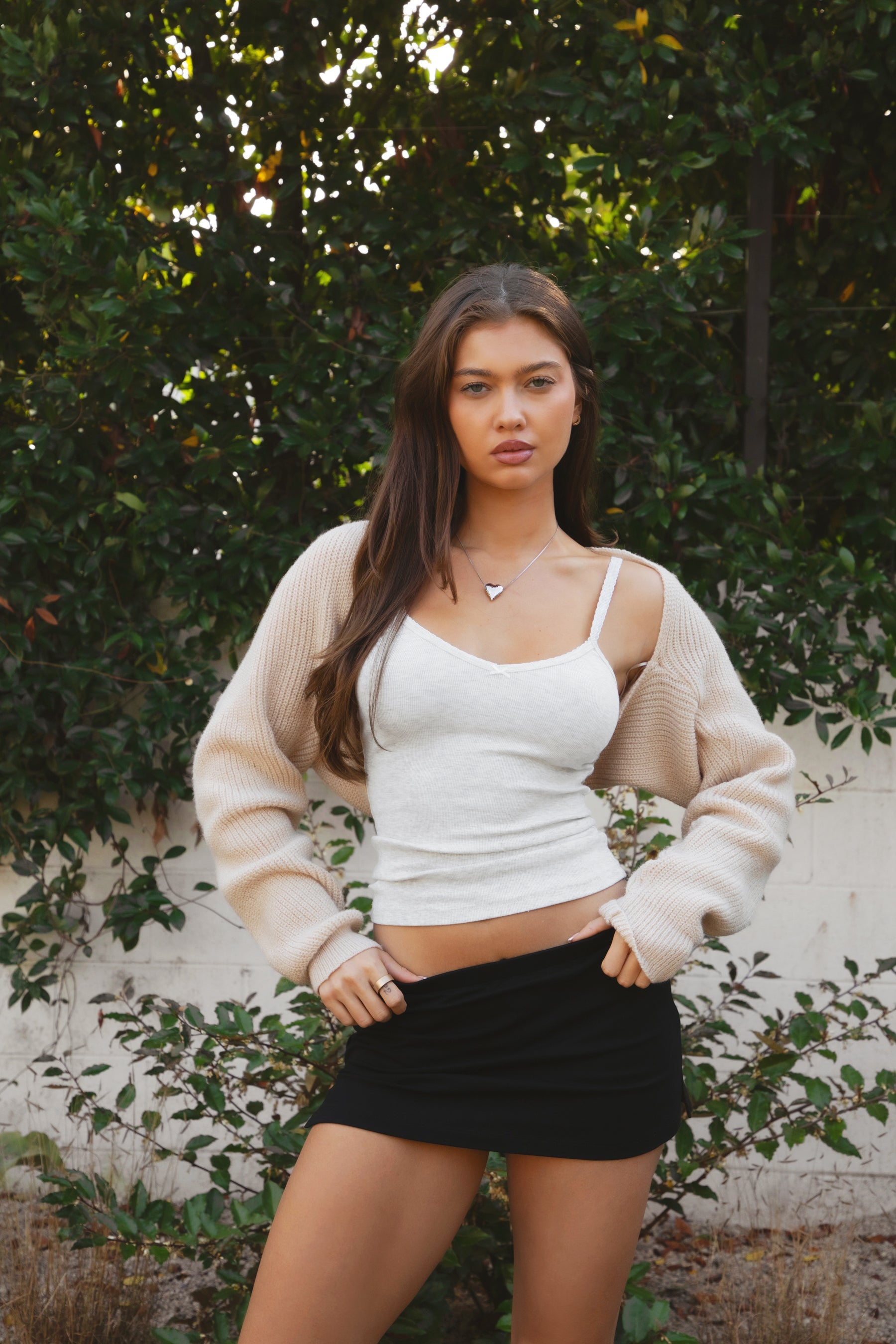 Woman wearing TIC TOC TC28065-FLUFF FLUFF shrug style crop cardigan bolero featuring an open front construction, easy semi loose fit, ultra cropped hem at the waist, and long semi loose sleeves finished with ribbed fitted cuffs, styled layered over a fitted tank and high-rise bottoms for a light, versatile everyday look.