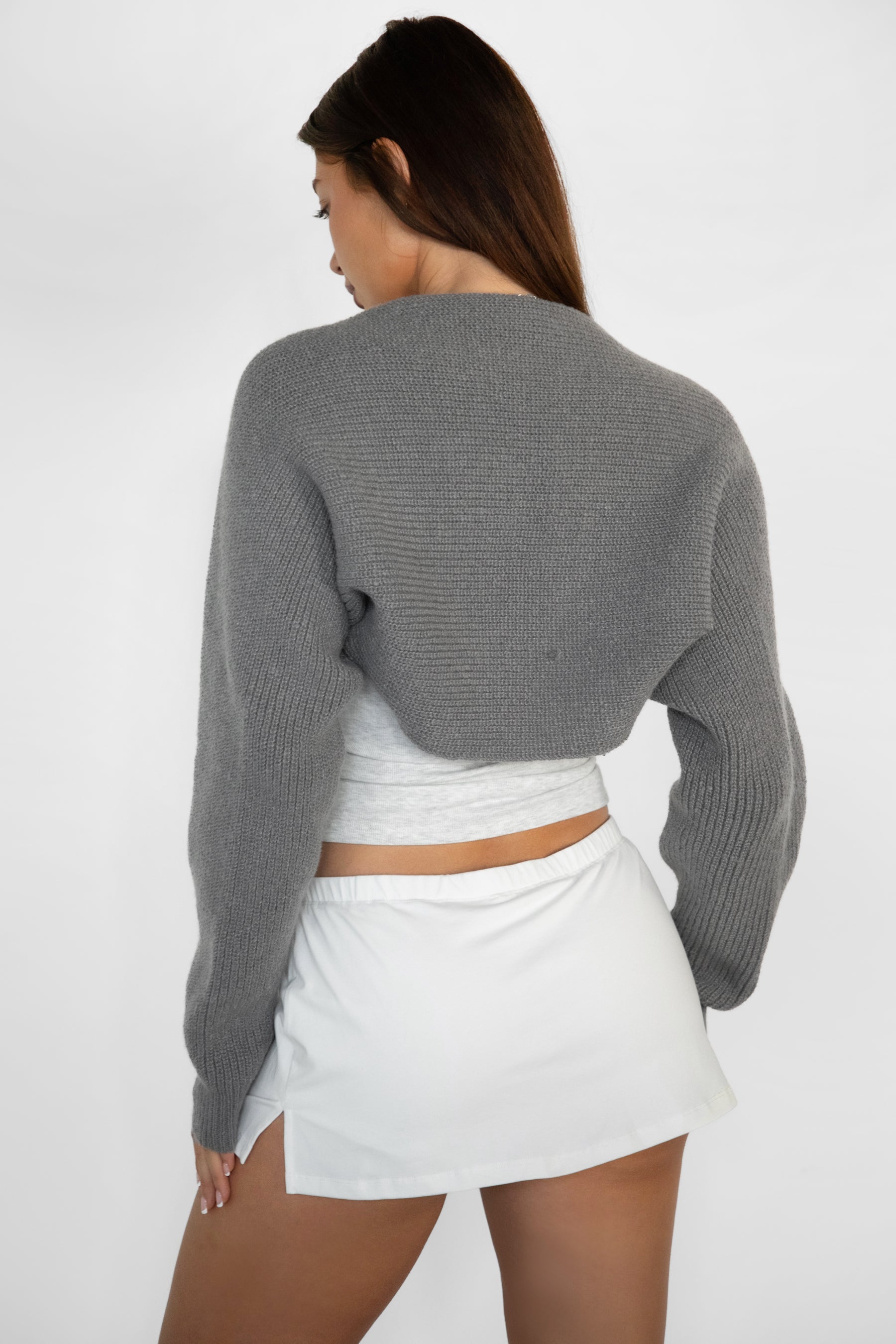 Woman wearing TIC TOC TC28065-FLUFF FLUFF shrug style crop cardigan bolero featuring an open front construction, easy semi loose fit, ultra cropped hem at the waist, and long semi loose sleeves finished with ribbed fitted cuffs, styled layered over a fitted tank and high-rise bottoms for a light, versatile everyday look.