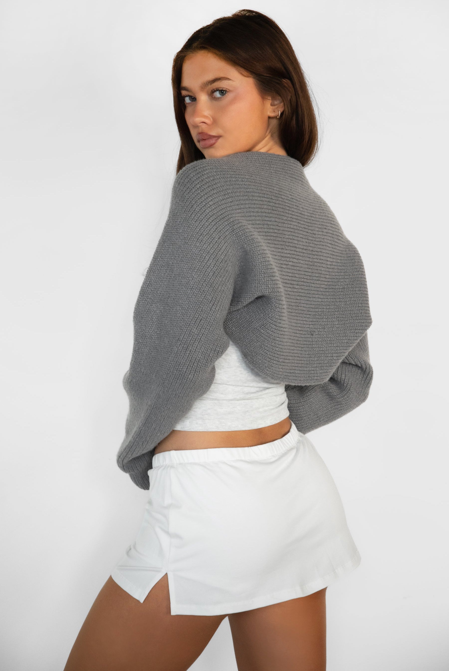 Woman wearing TIC TOC TC28065-FLUFF FLUFF shrug style crop cardigan bolero featuring an open front construction, easy semi loose fit, ultra cropped hem at the waist, and long semi loose sleeves finished with ribbed fitted cuffs, styled layered over a fitted tank and high-rise bottoms for a light, versatile everyday look.