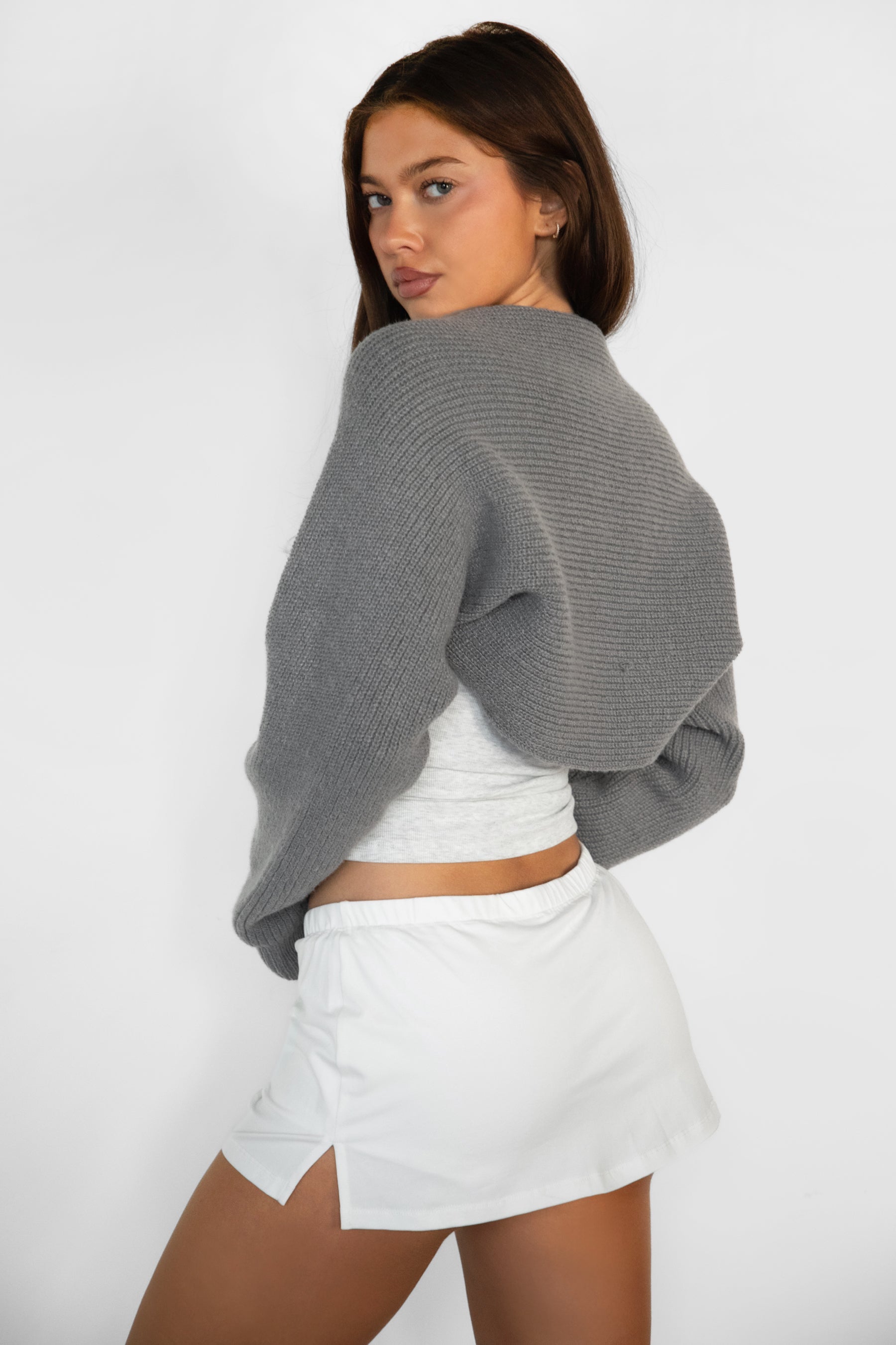 Woman wearing TIC TOC TC28065-FLUFF FLUFF shrug style crop cardigan bolero featuring an open front construction, easy semi loose fit, ultra cropped hem at the waist, and long semi loose sleeves finished with ribbed fitted cuffs, styled layered over a fitted tank and high-rise bottoms for a light, versatile everyday look.