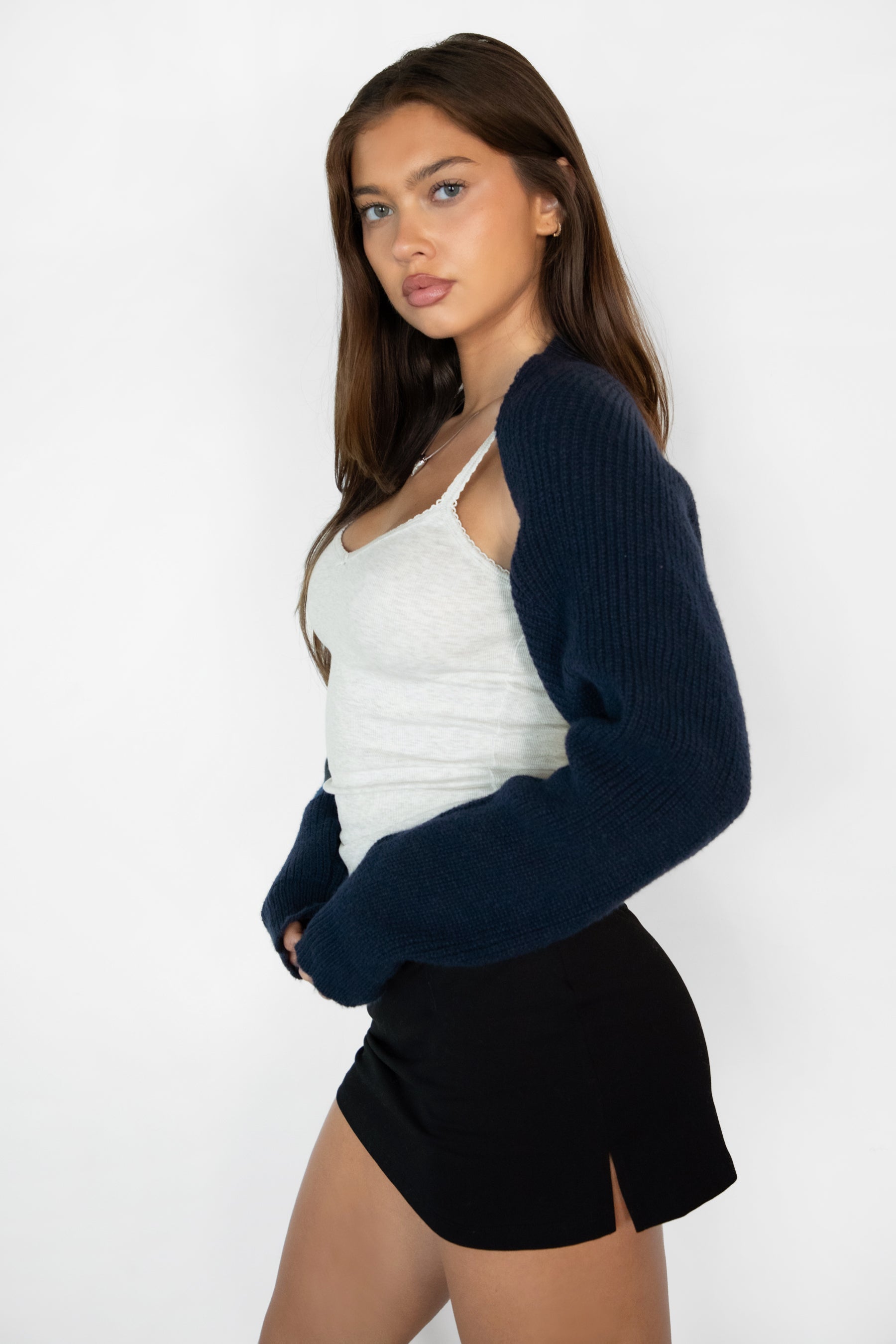 Woman wearing TIC TOC TC28065-FLUFF FLUFF shrug style crop cardigan bolero featuring an open front construction, easy semi loose fit, ultra cropped hem at the waist, and long semi loose sleeves finished with ribbed fitted cuffs, styled layered over a fitted tank and high-rise bottoms for a light, versatile everyday look.