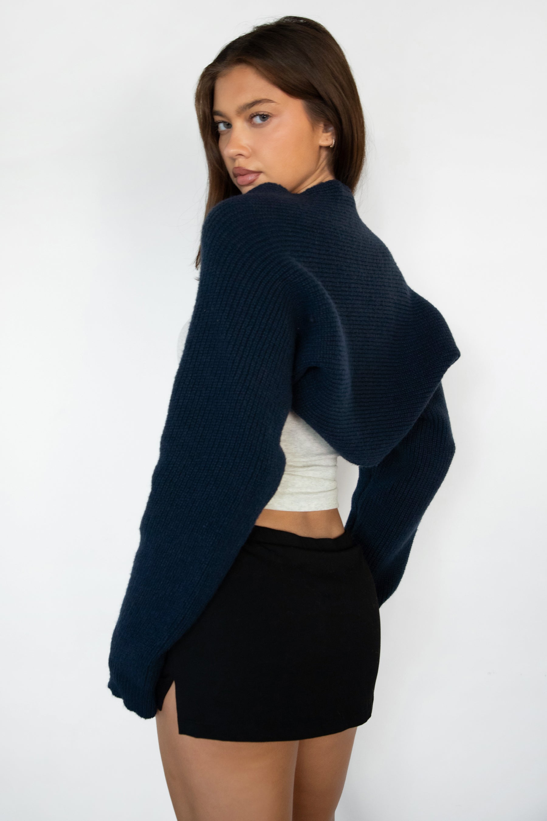 Woman wearing TIC TOC TC28065-FLUFF FLUFF shrug style crop cardigan bolero featuring an open front construction, easy semi loose fit, ultra cropped hem at the waist, and long semi loose sleeves finished with ribbed fitted cuffs, styled layered over a fitted tank and high-rise bottoms for a light, versatile everyday look.