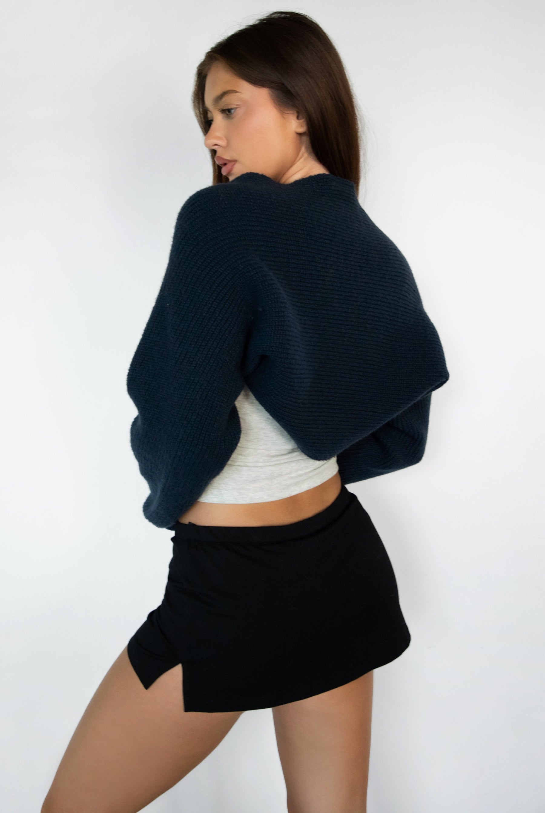 Woman wearing TIC TOC TC28065-FLUFF FLUFF shrug style crop cardigan bolero featuring an open front construction, easy semi loose fit, ultra cropped hem at the waist, and long semi loose sleeves finished with ribbed fitted cuffs, styled layered over a fitted tank and high-rise bottoms for a light, versatile everyday look.