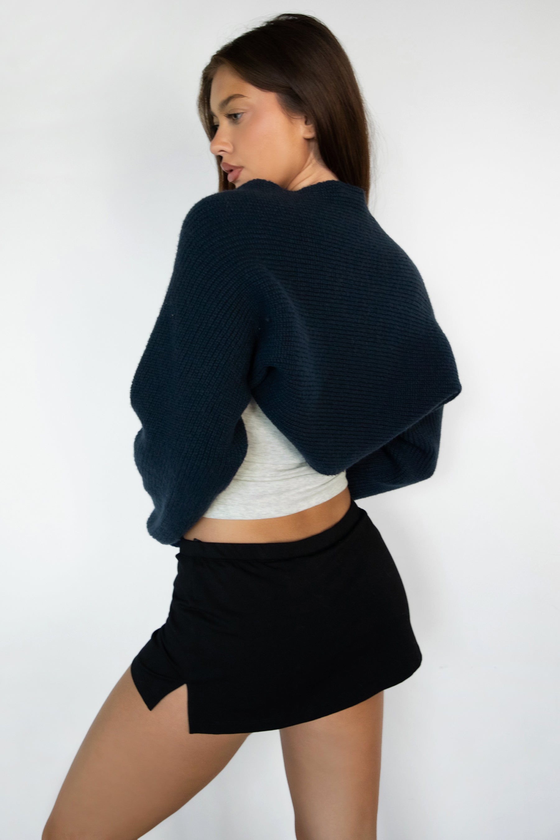 Woman wearing TIC TOC TC28065-FLUFF FLUFF shrug style crop cardigan bolero featuring an open front construction, easy semi loose fit, ultra cropped hem at the waist, and long semi loose sleeves finished with ribbed fitted cuffs, styled layered over a fitted tank and high-rise bottoms for a light, versatile everyday look.