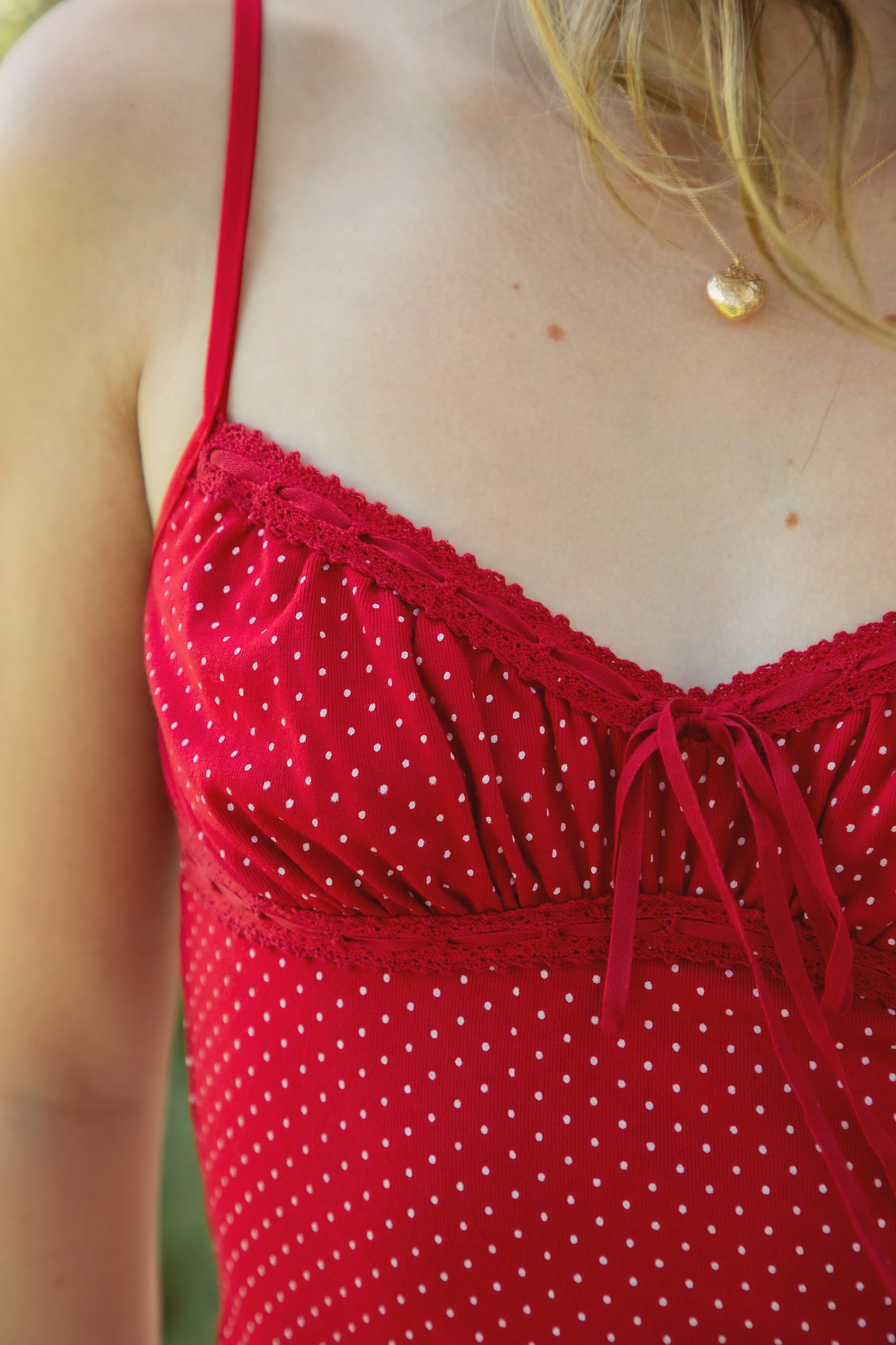 Woman wearing LOTTIE polka dot print lace contrast jersey tank featuring a delicate polka dot print, V-neckline with self-tie bow detail, lace trim along the neckline and under bust, adjustable thin straps, and a soft stretch jersey body-skimming silhouette.