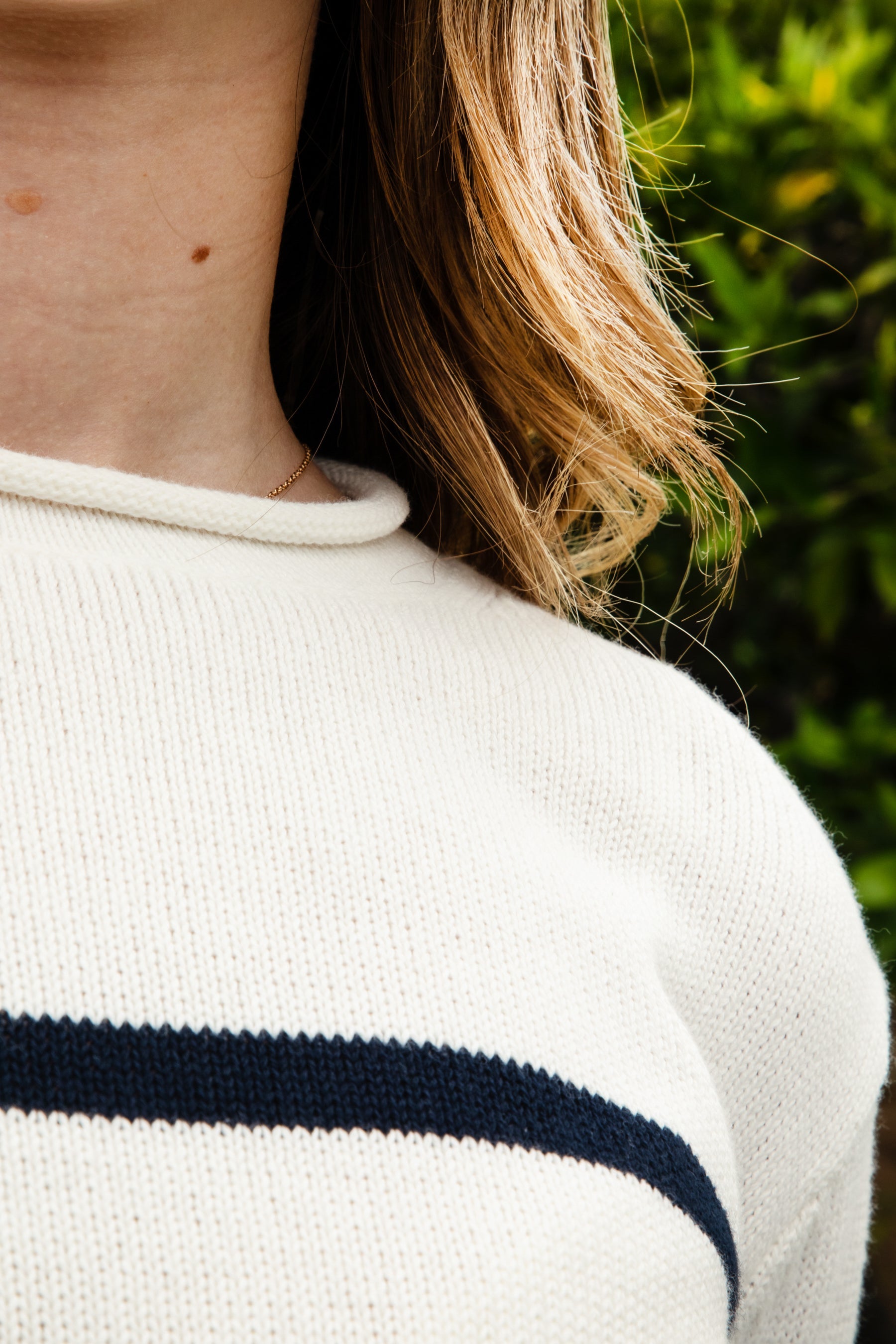 Woman wearing WINSLOW striped cable knit long sleeve sweater featuring a classic rolled neckline, contrast stripe design, soft cotton cable knit fabric, long sleeves with ribbed cuffs and hem, and a relaxed mid-length silhouette for effortless everyday layering.