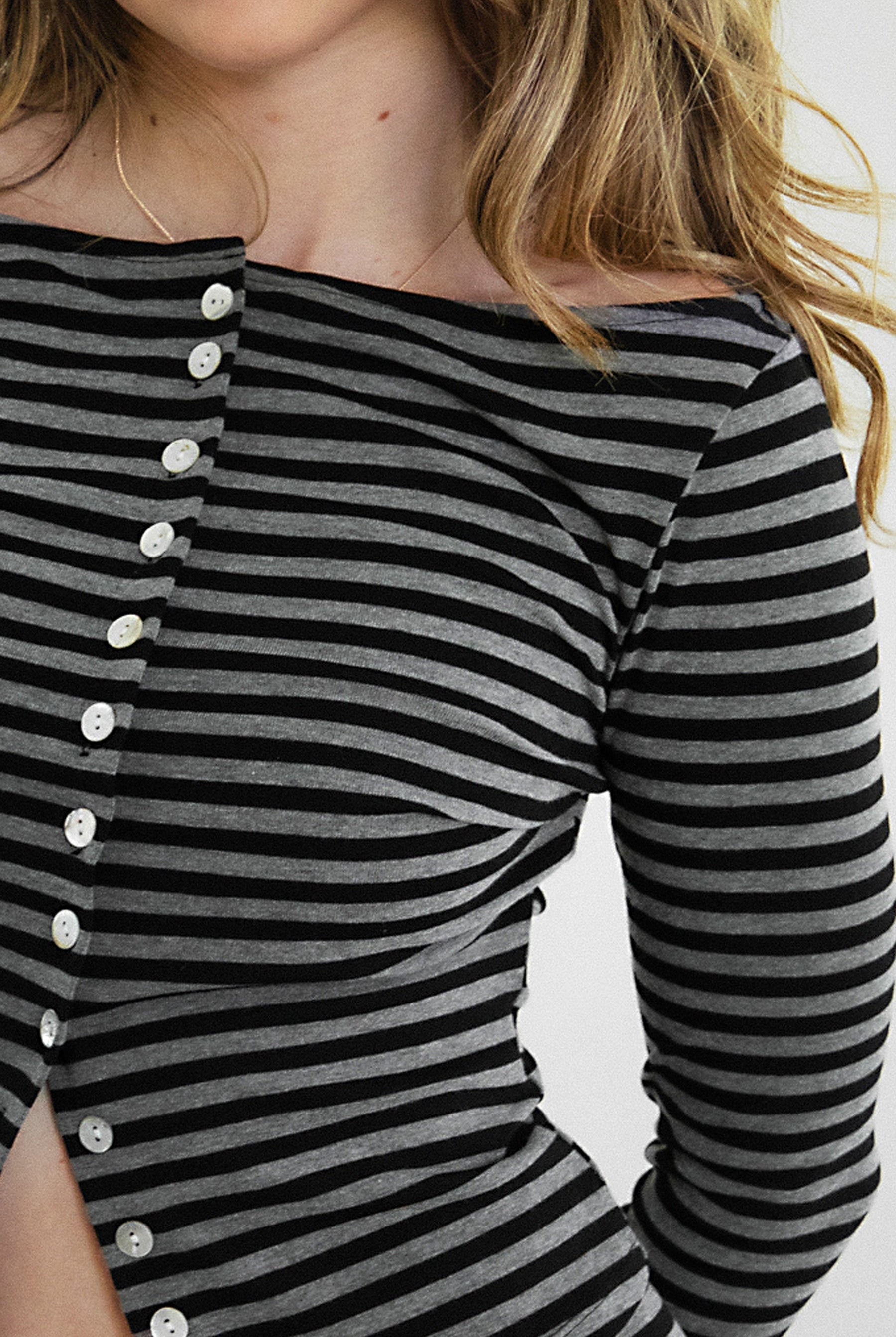 Woman wearing VELA stripe jersey long sleeve cardigan featuring a classic stripe pattern, boat neckline, front button closure, long sleeves, and soft stretch jersey fabric designed to pair with coordinating VELA micro shorts for cozy lounge and casual styling.